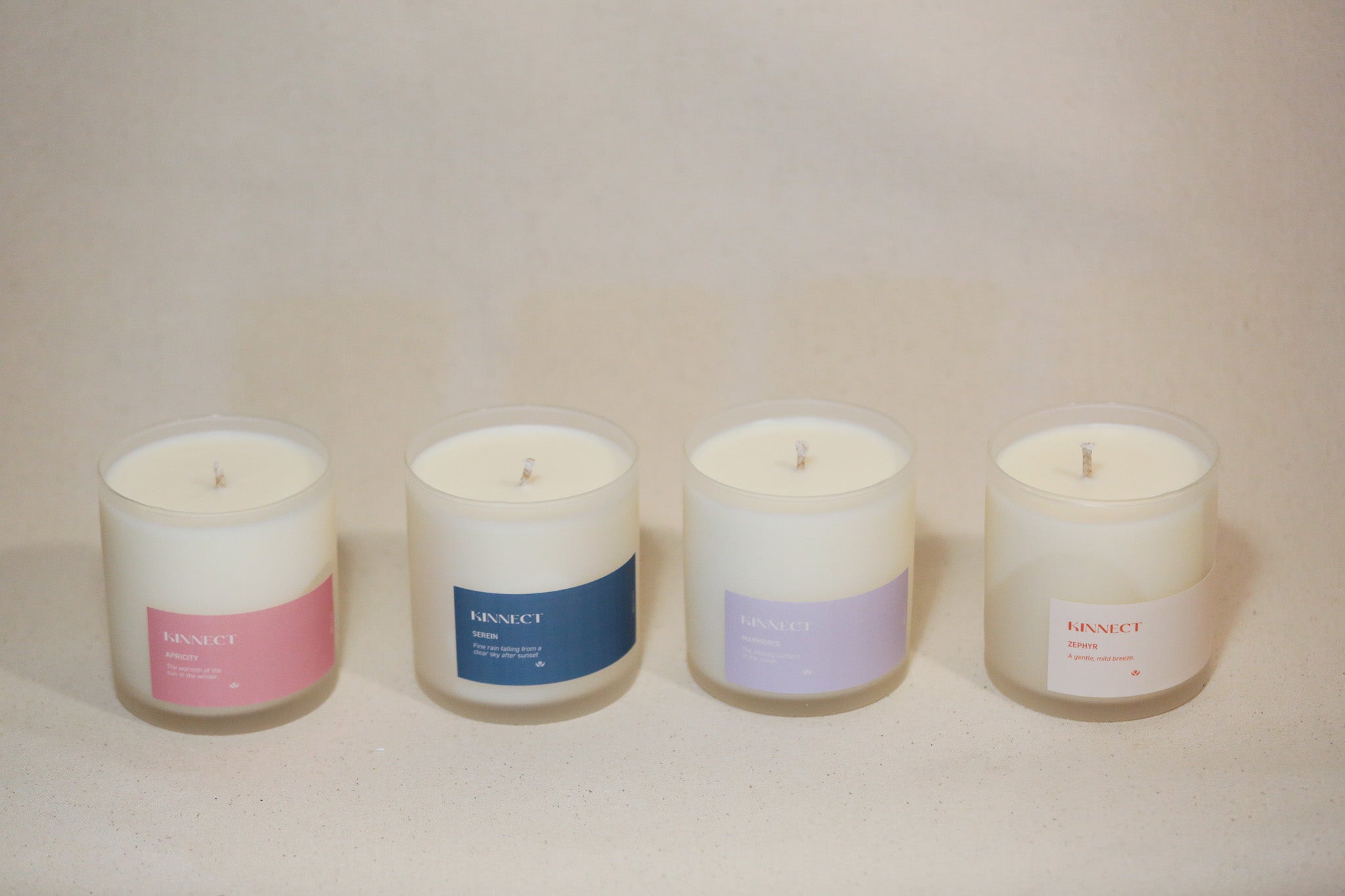 Four candles of different colors with visible “Kinnect” branding on a neutral background