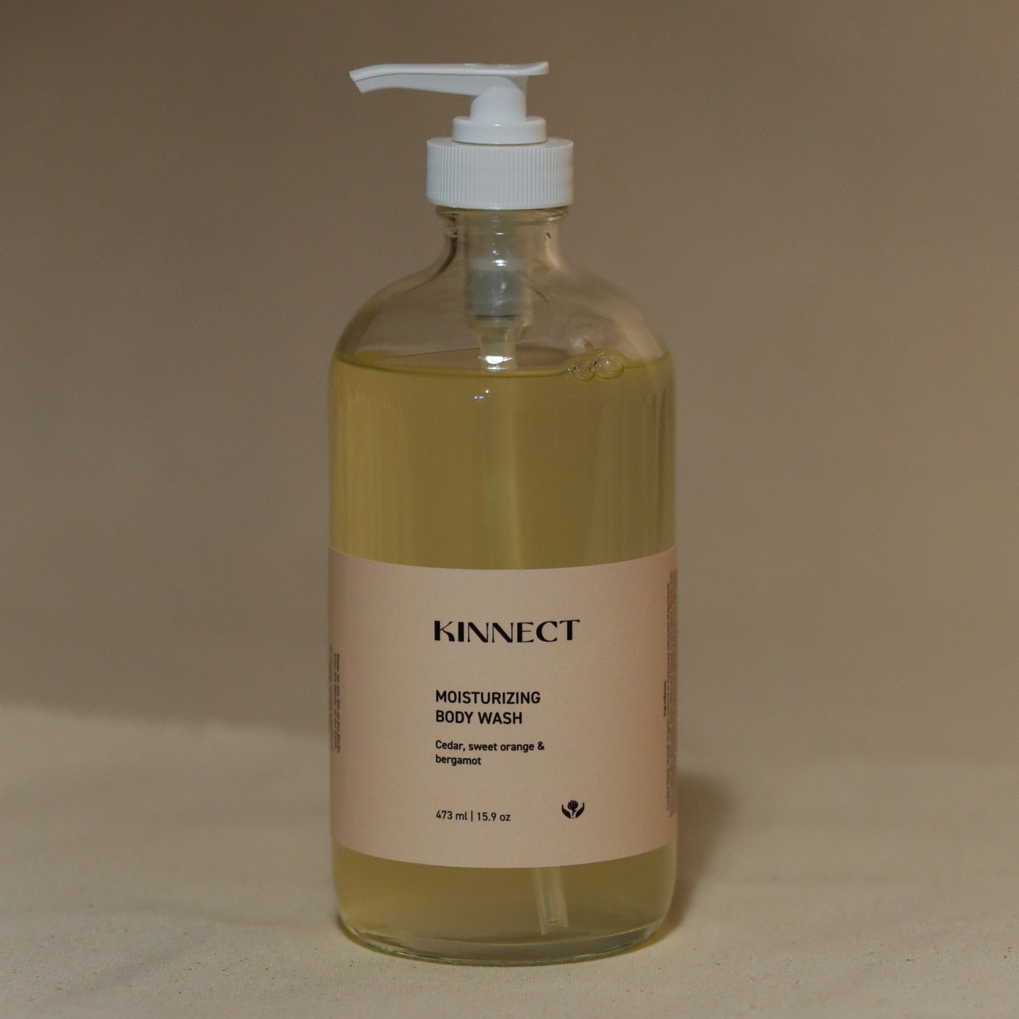Clear bottle of Kinnect moisturizing body wash on a beige background