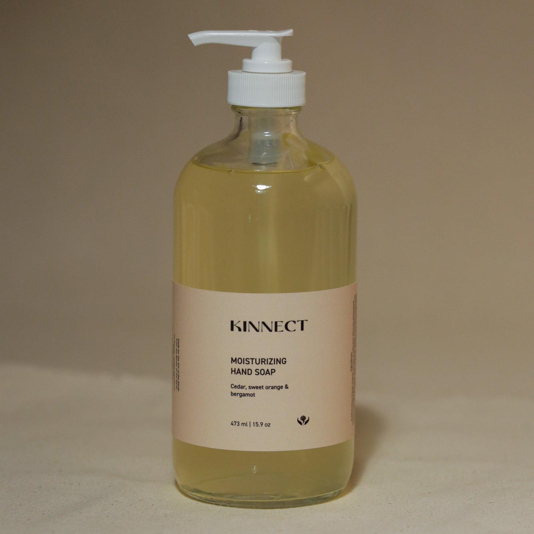 Glass bottle of kinnect moisturizing hand soap on a beige background