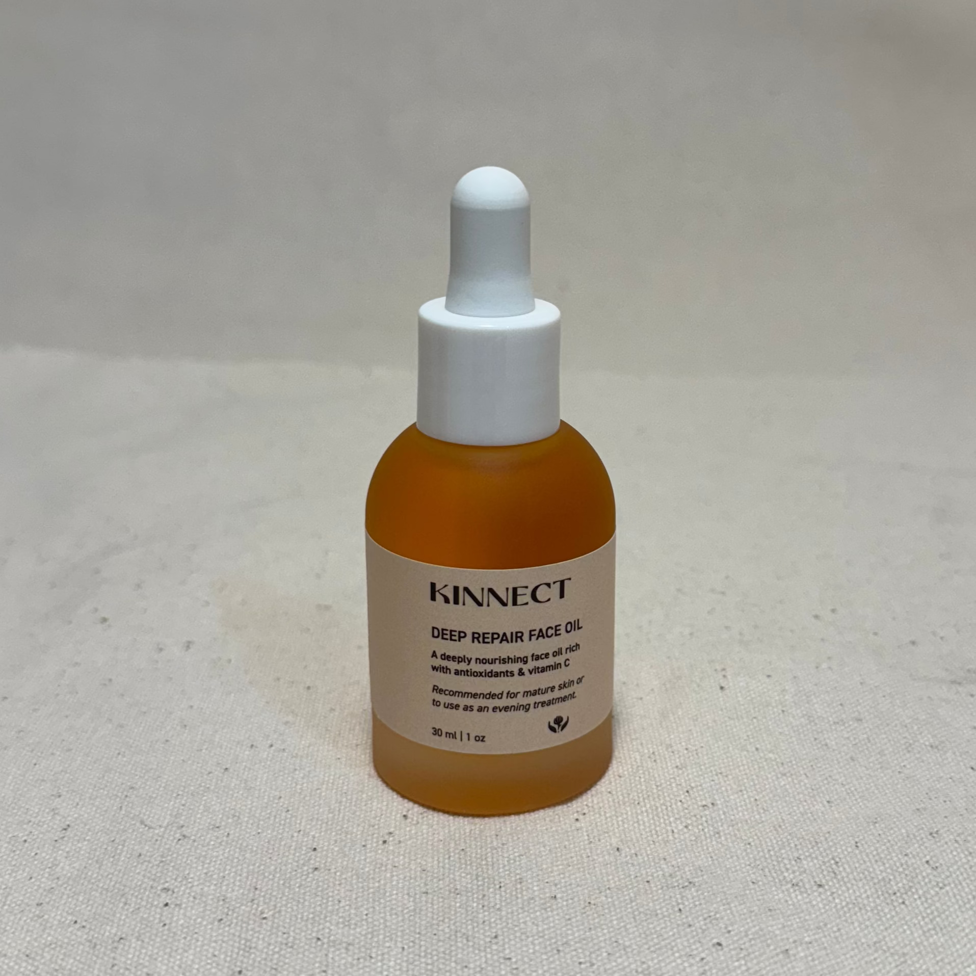 Bottle of KINNECT Deep Repair Face Oil on a light gray background