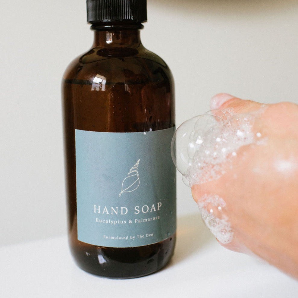 The Den Refillery Eucalyptus and palmarosa hand soap / body wash being used as a hand soap. It comes in our signature amber bottles with blue labels