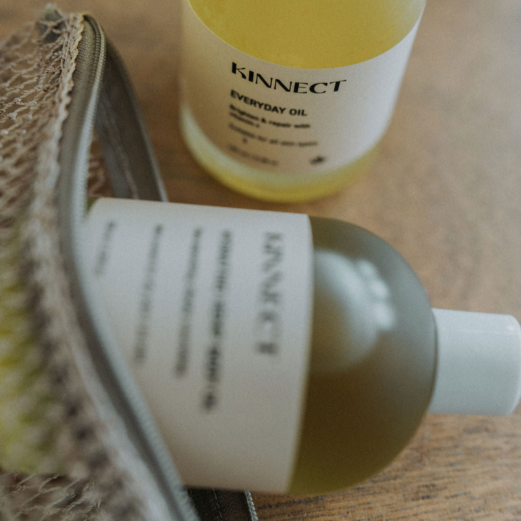 Two bottles of 'KINNECT' oil on a wooden surface