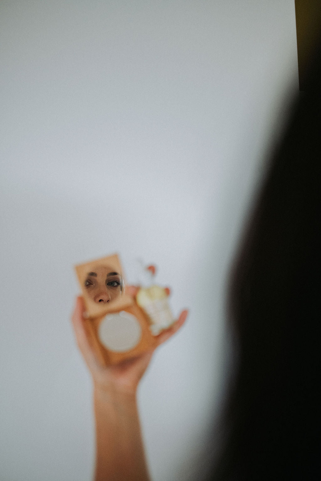 Model holds compact mirror and balance and hydrate face oil to the camera