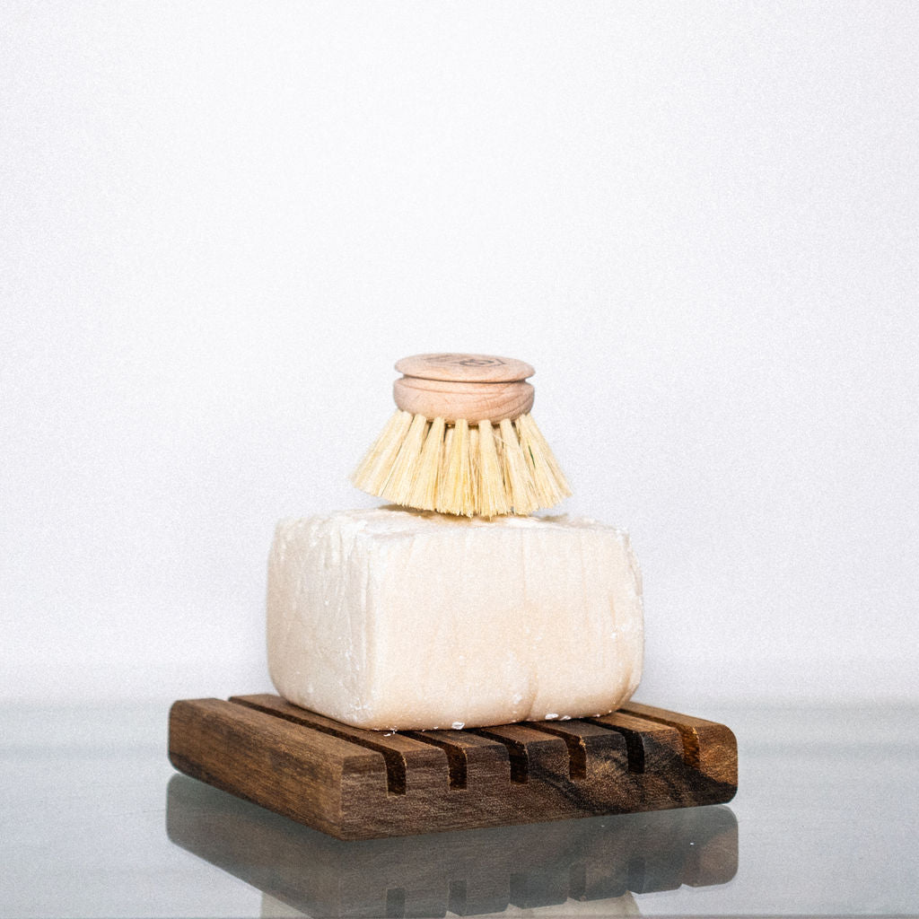 Dish soap cube on a wooden soap dish with a dish brush on top