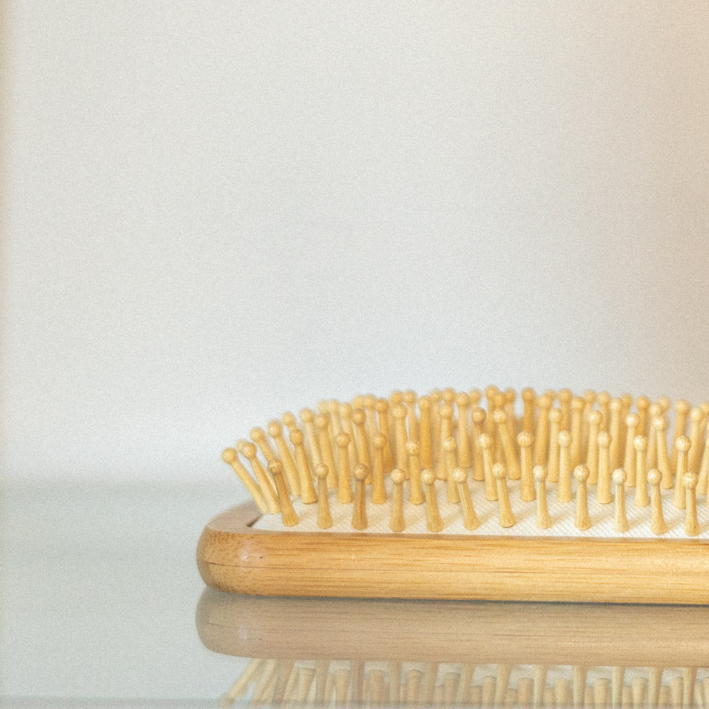 Close-up photo of a bamboo hairbrush on a glass surface