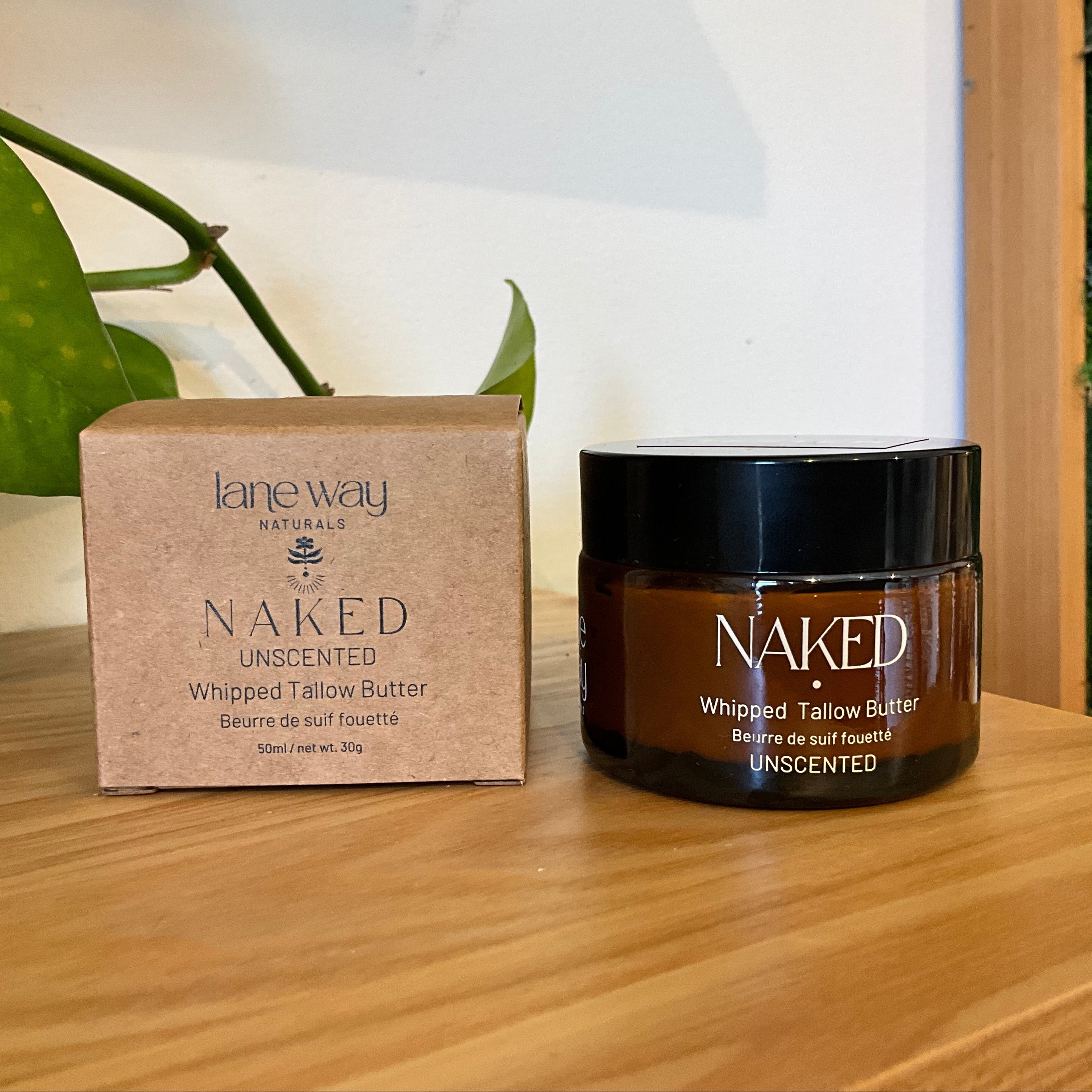 Lane Way Naked Unscented Whipped Tallow Butter shown with its brown kraft paper box and a dark amber jar on a wooden surface.