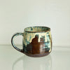 Earth and fibre studio mug with a white and blue glaze over dark brown/red clay