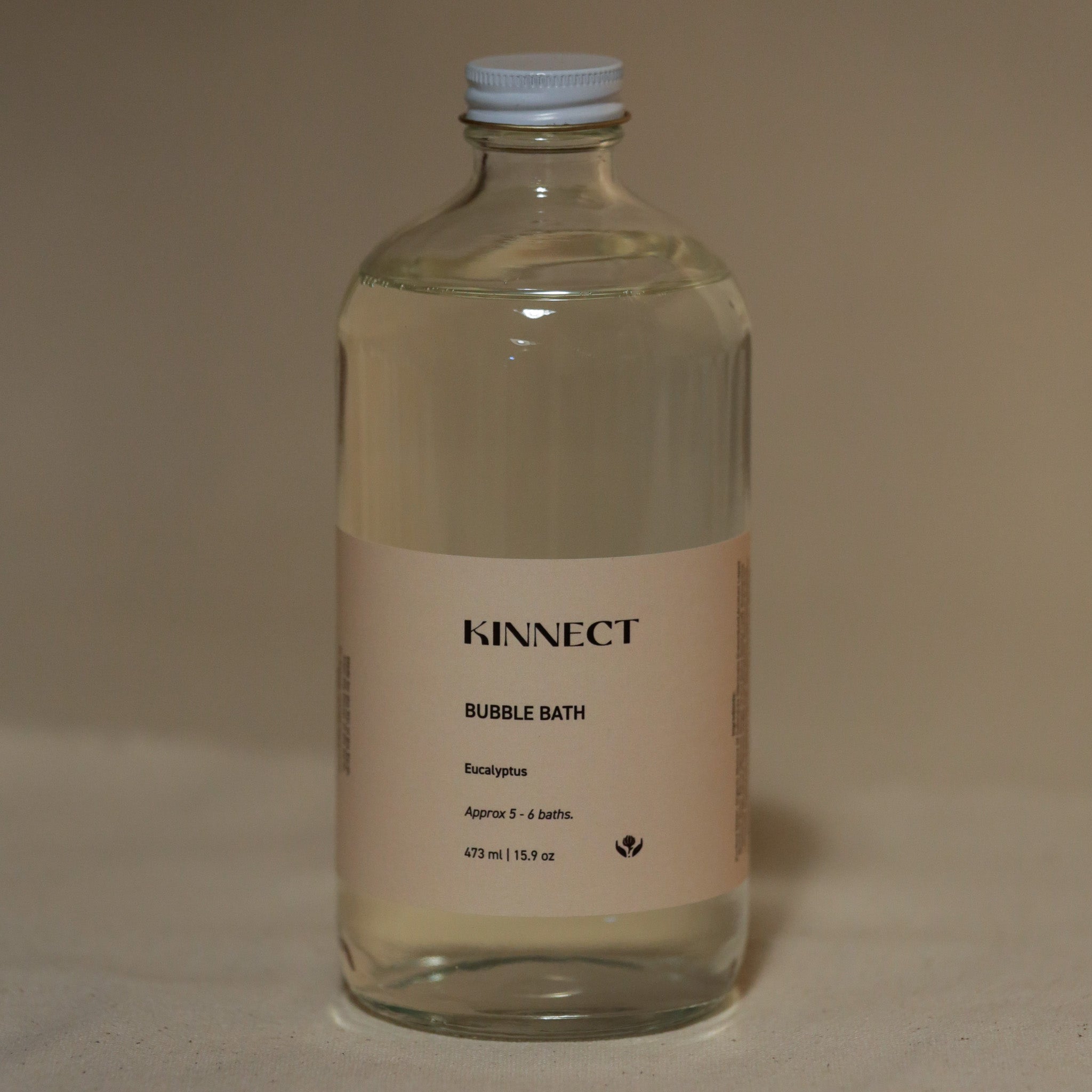 Clear bottle of KINNECT bubble bath on a beige background