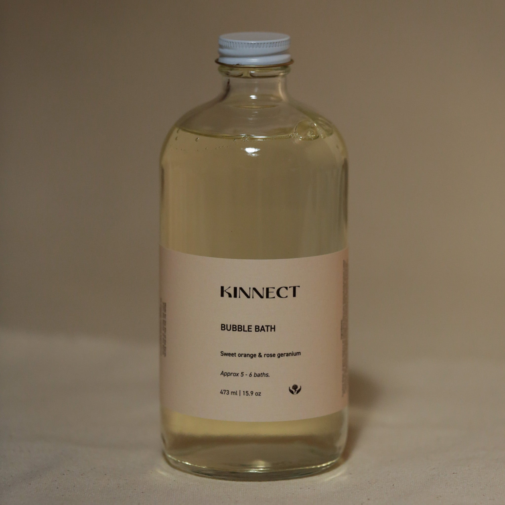 Glass bottle of Kinnect bubble bath on a beige background