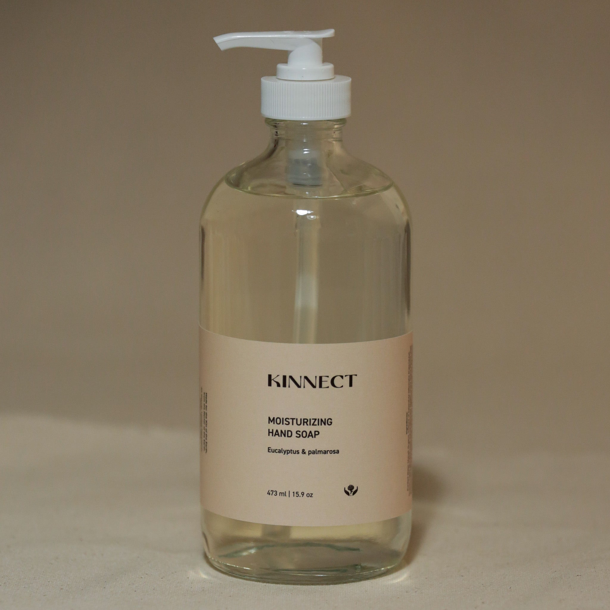 Glass bottle of KINNECT moisturizing hand soap on a beige background