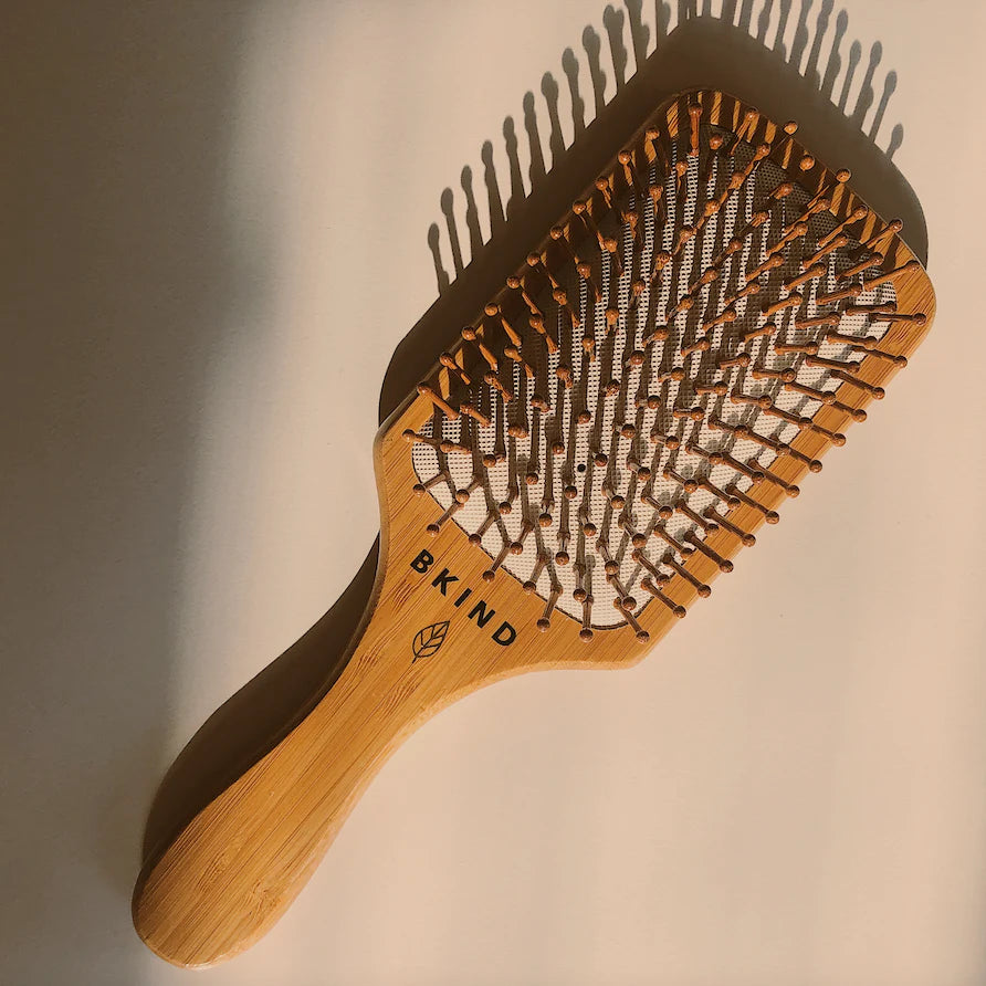 Hairbrush with wooden handle and brown bristles on a neutral background