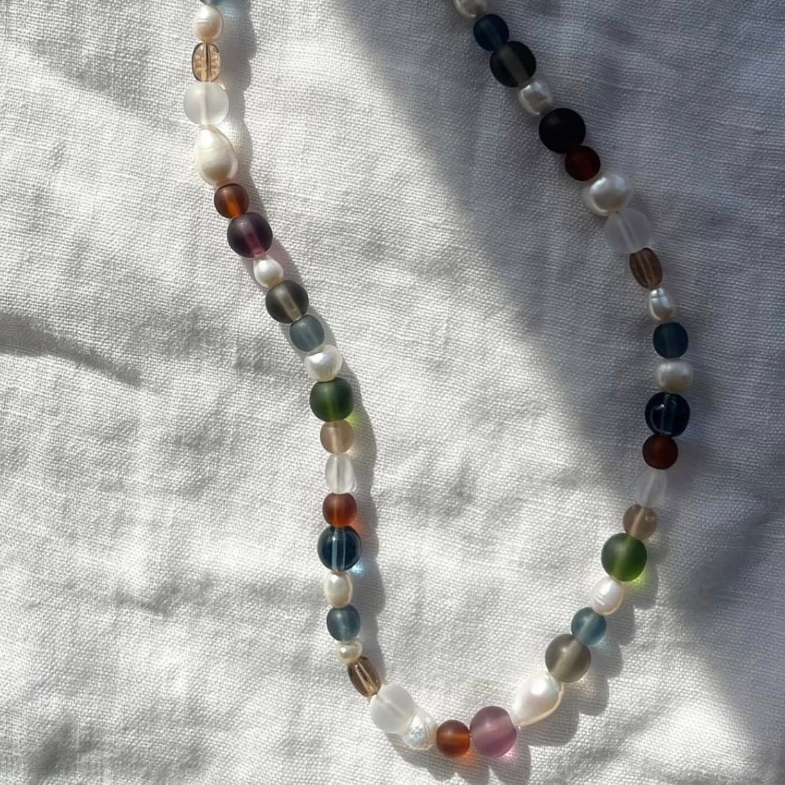 Beaded necklace with multicolored beads on a light fabric background