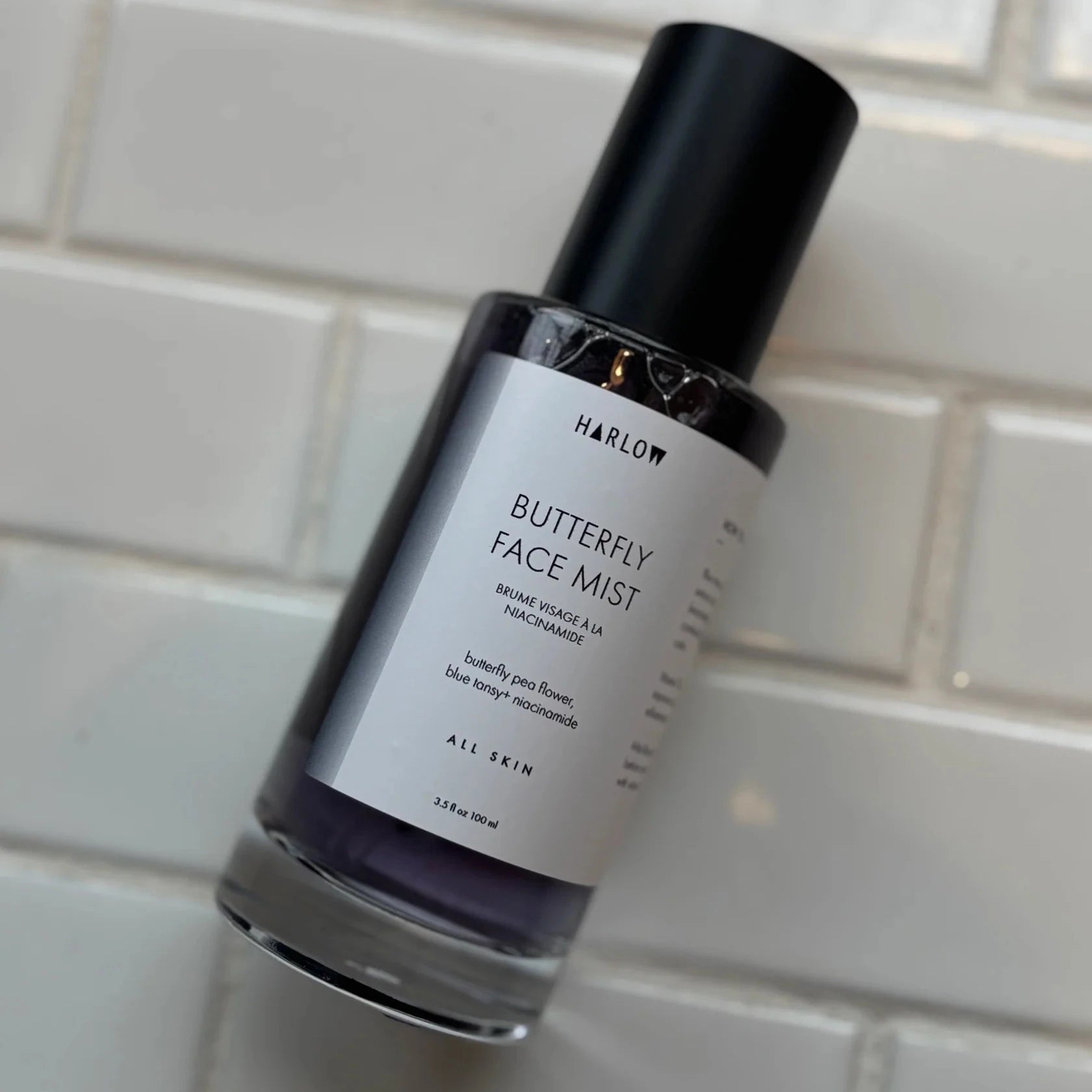 Butterfly Face Mist bottle with 'Harlow' branding on a tiled wall background