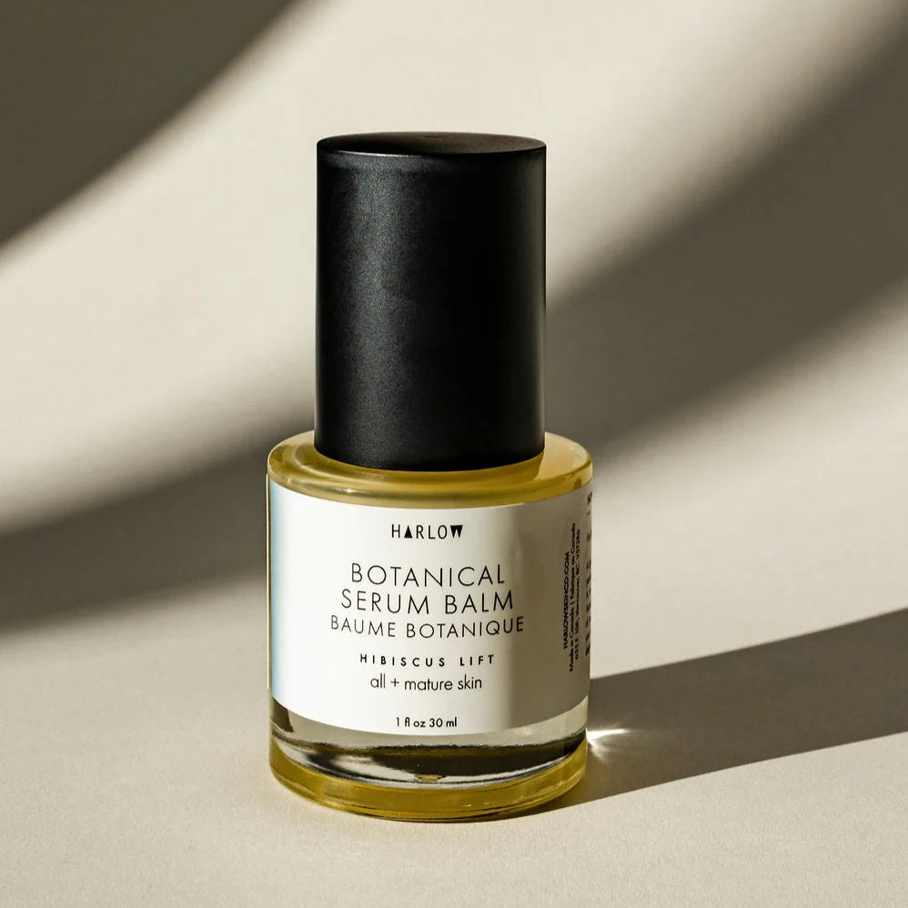 Botanical serum balm bottle with black cap on a beige background