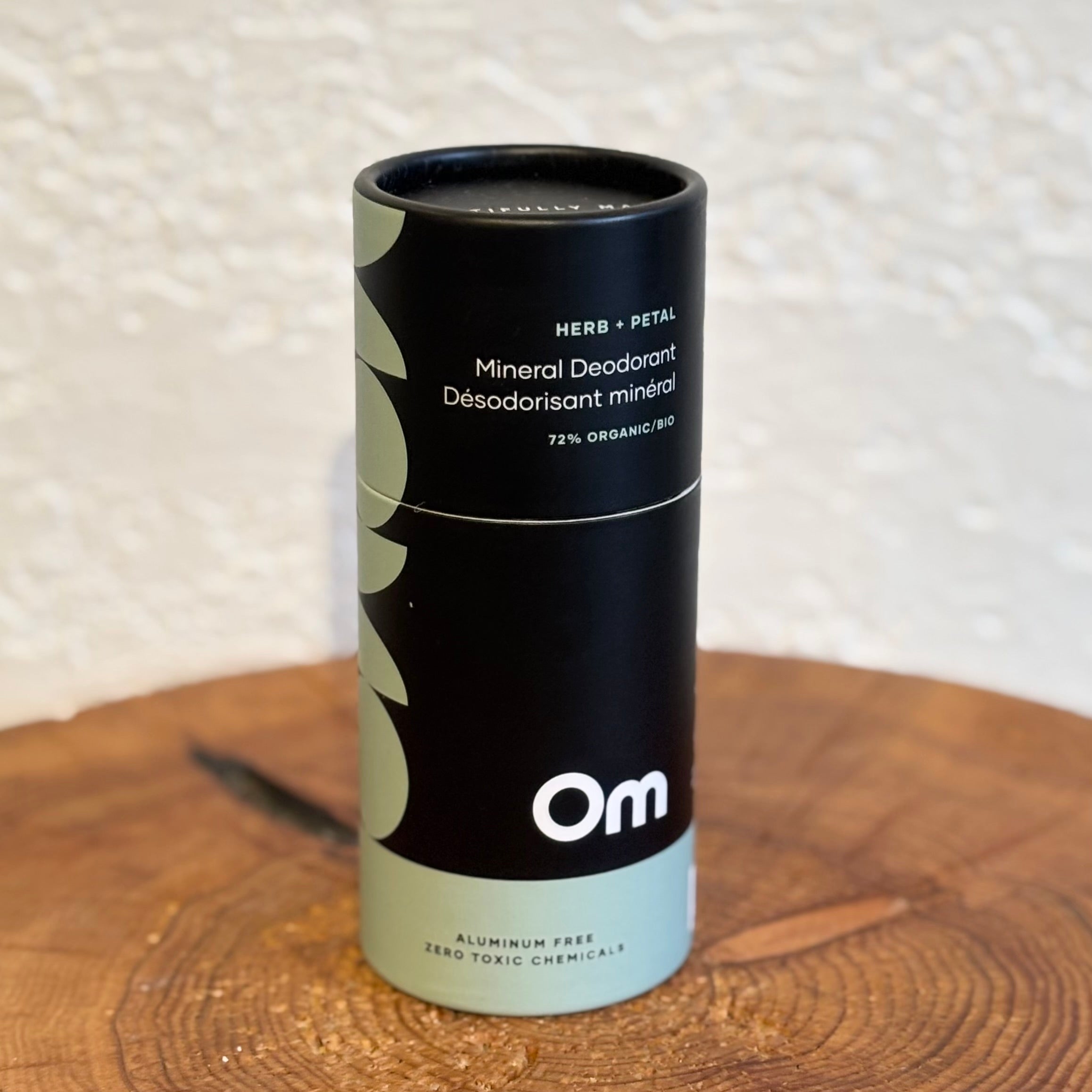 Mineral deodorant container with 'Om' branding on a wooden surface.
