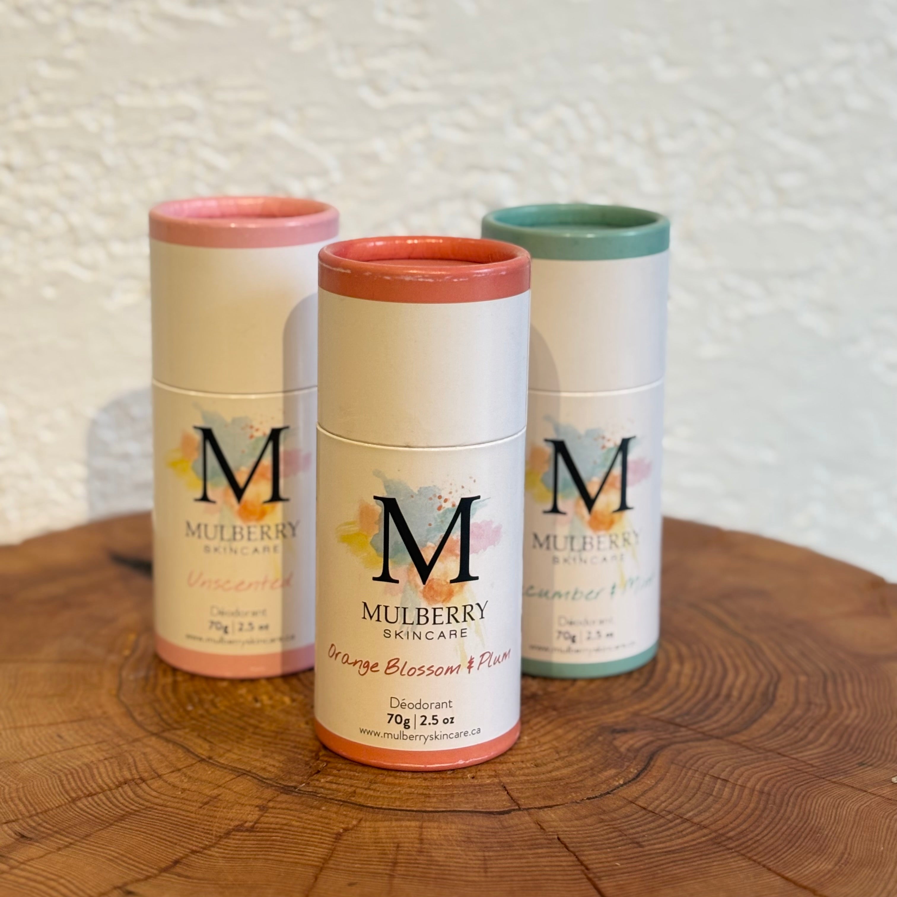 Three Mulberry Skincare products on a wooden surface with a textured white wall background.