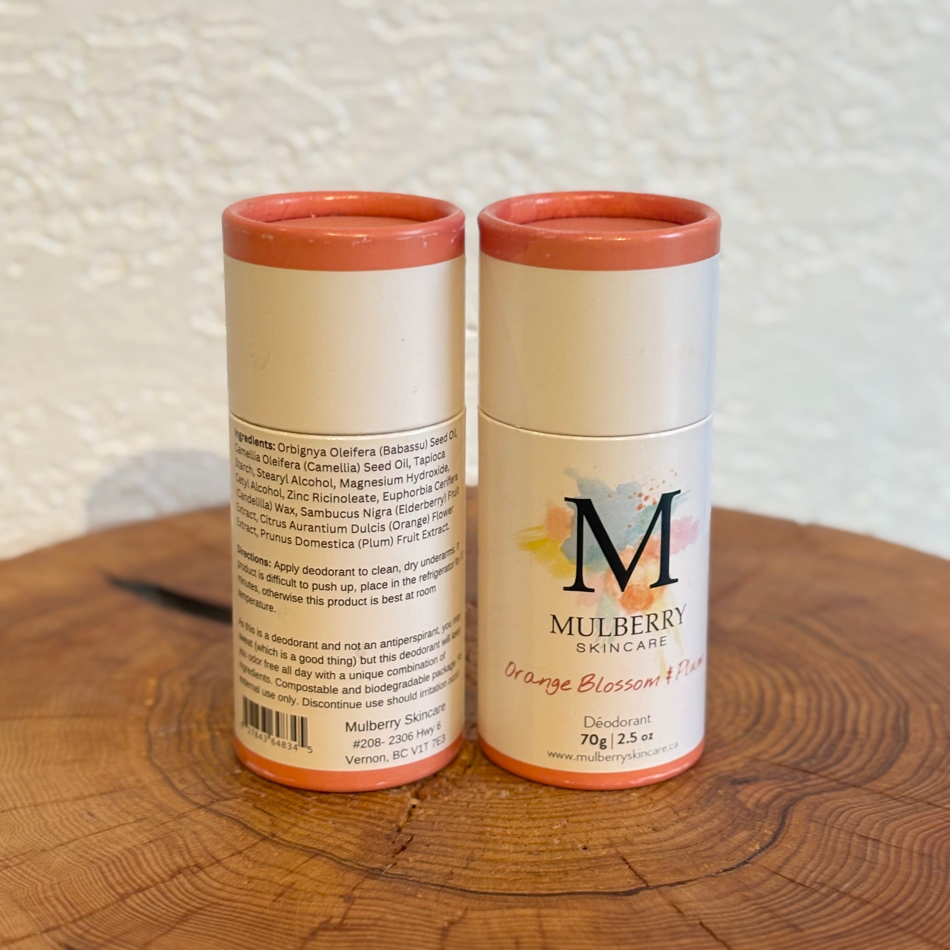 Two Mulberry Skincare deodorant containers on a wooden surface with a textured white background.