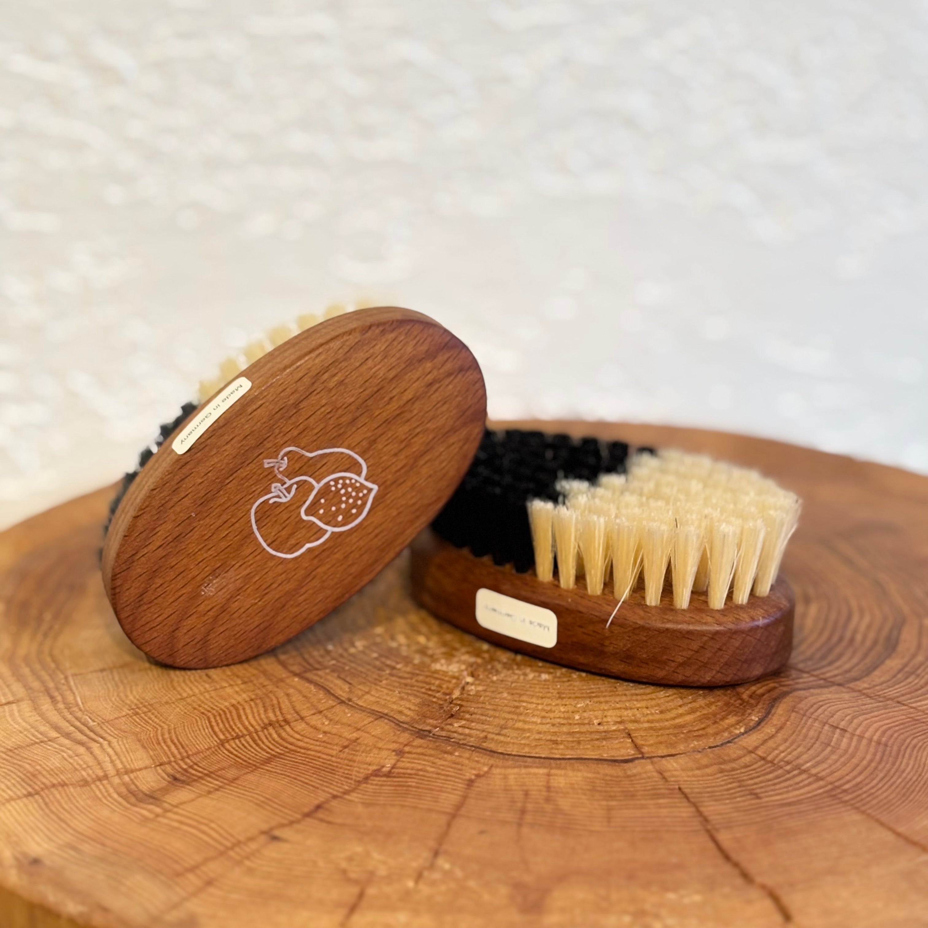 Wooden brush set with bristle and soft brush heads on a wooden surface.