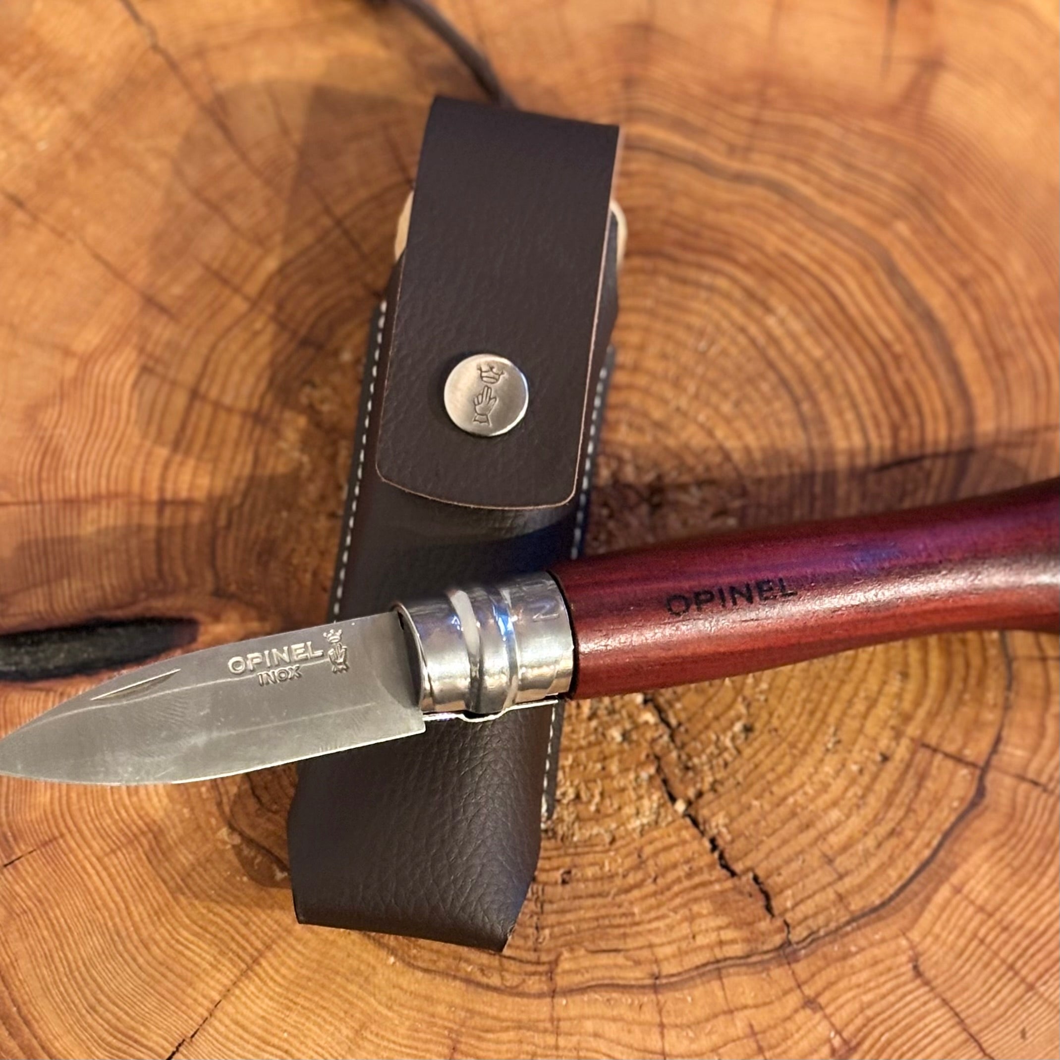 Opinel knife with leather sheath on a wooden surface