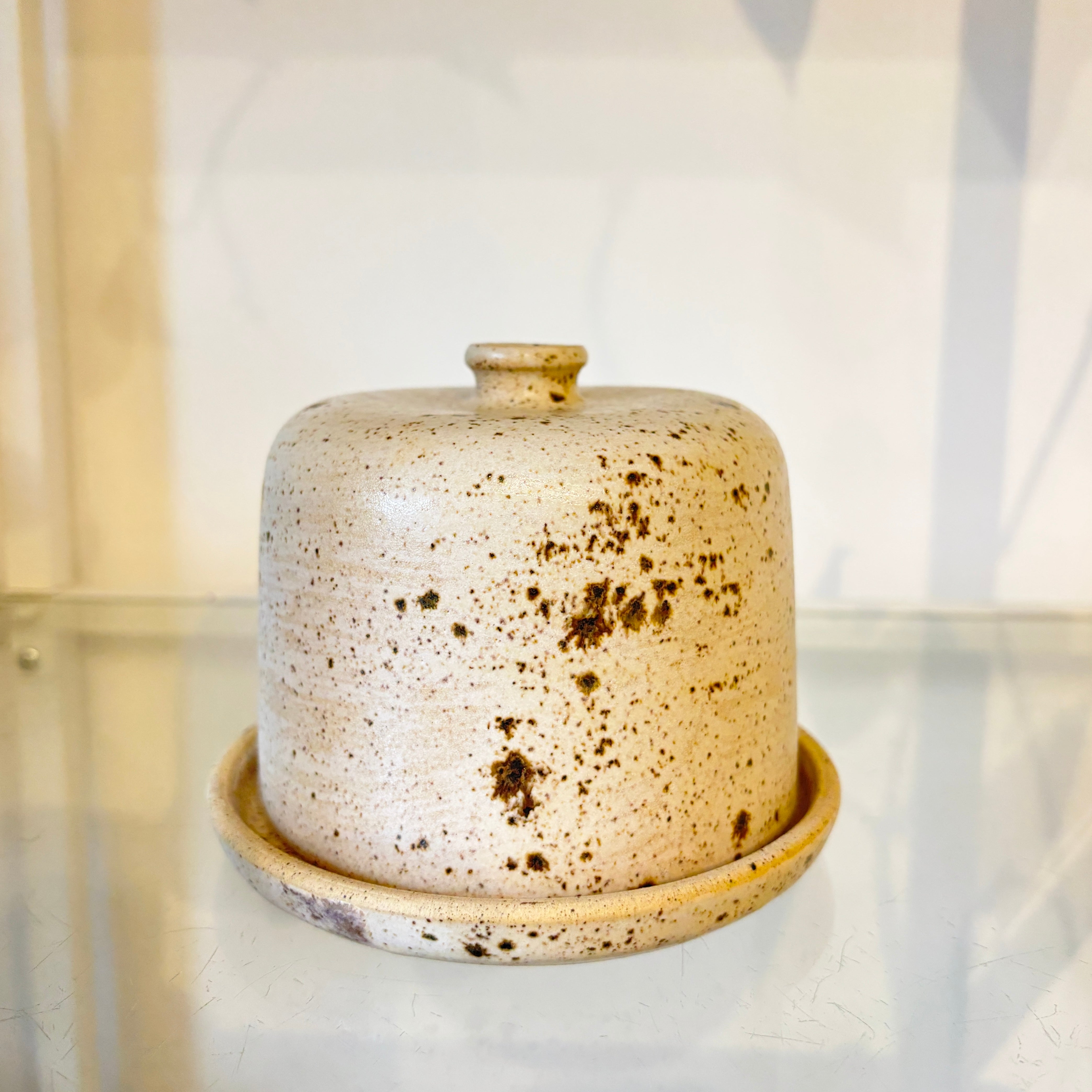 Speckled ceramic butter dish on a glass surface