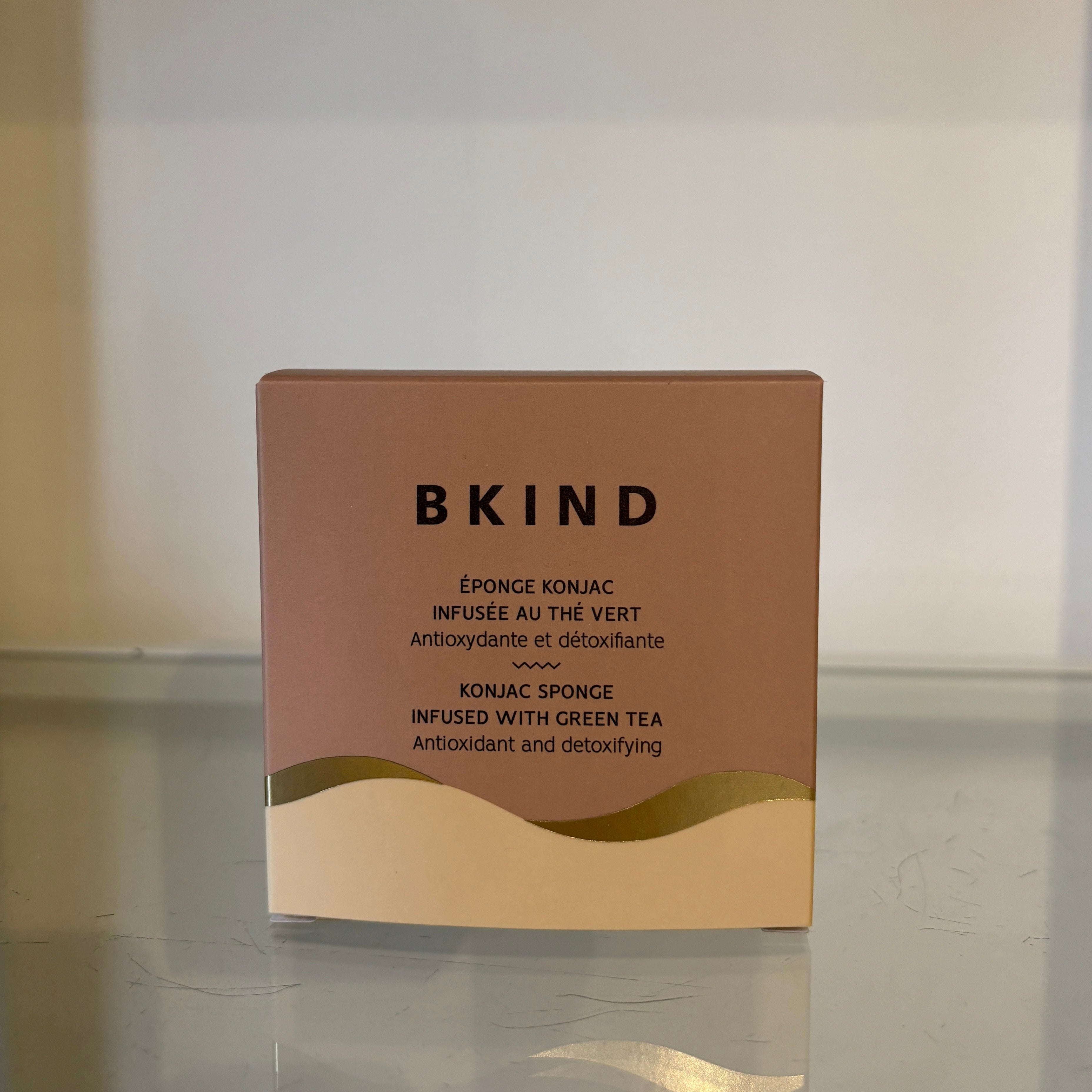BKIND Konjac sponge packaging with brown and beige design on a reflective surface.