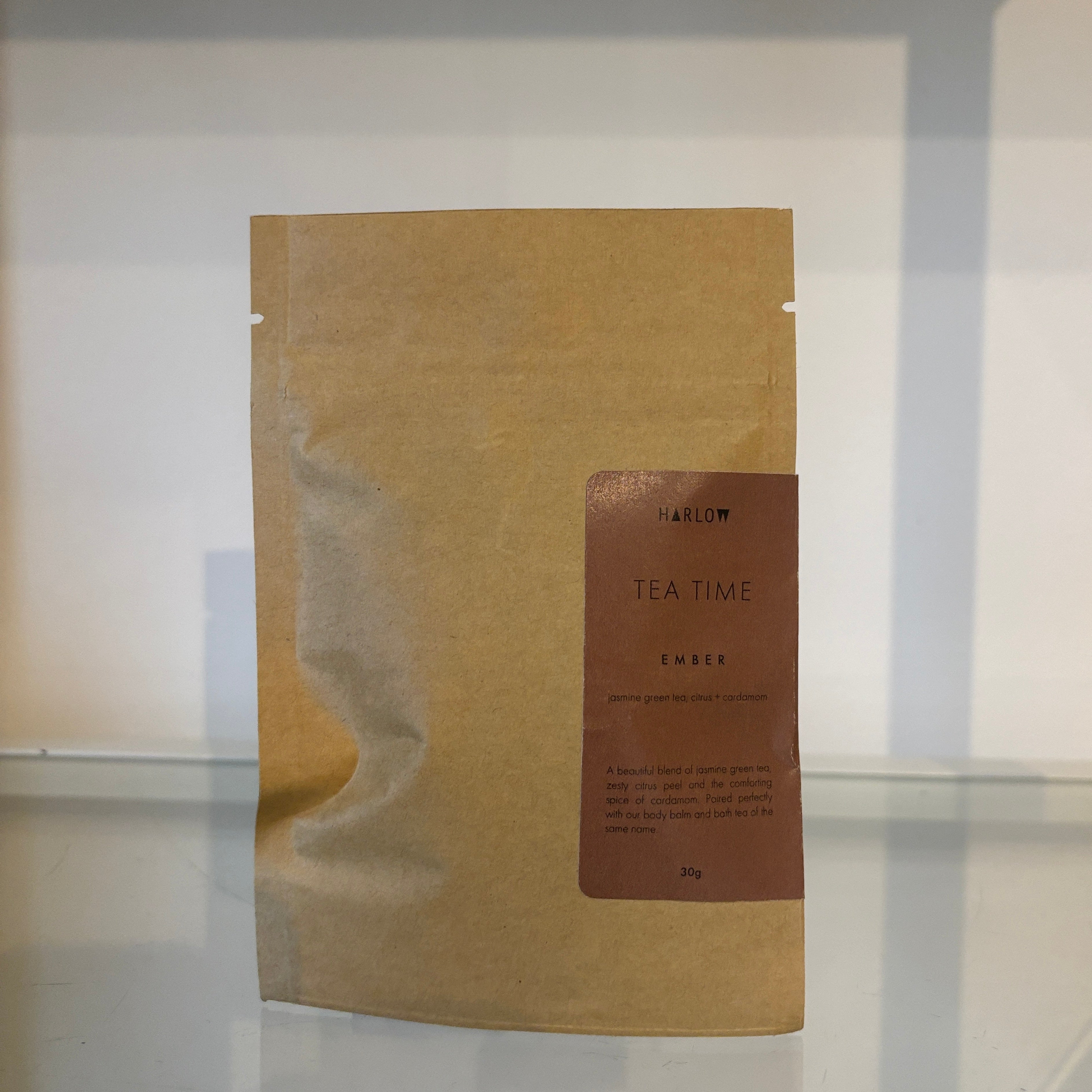 Brown paper tea bag with 'Harlow Tea Time' label on a reflective surface