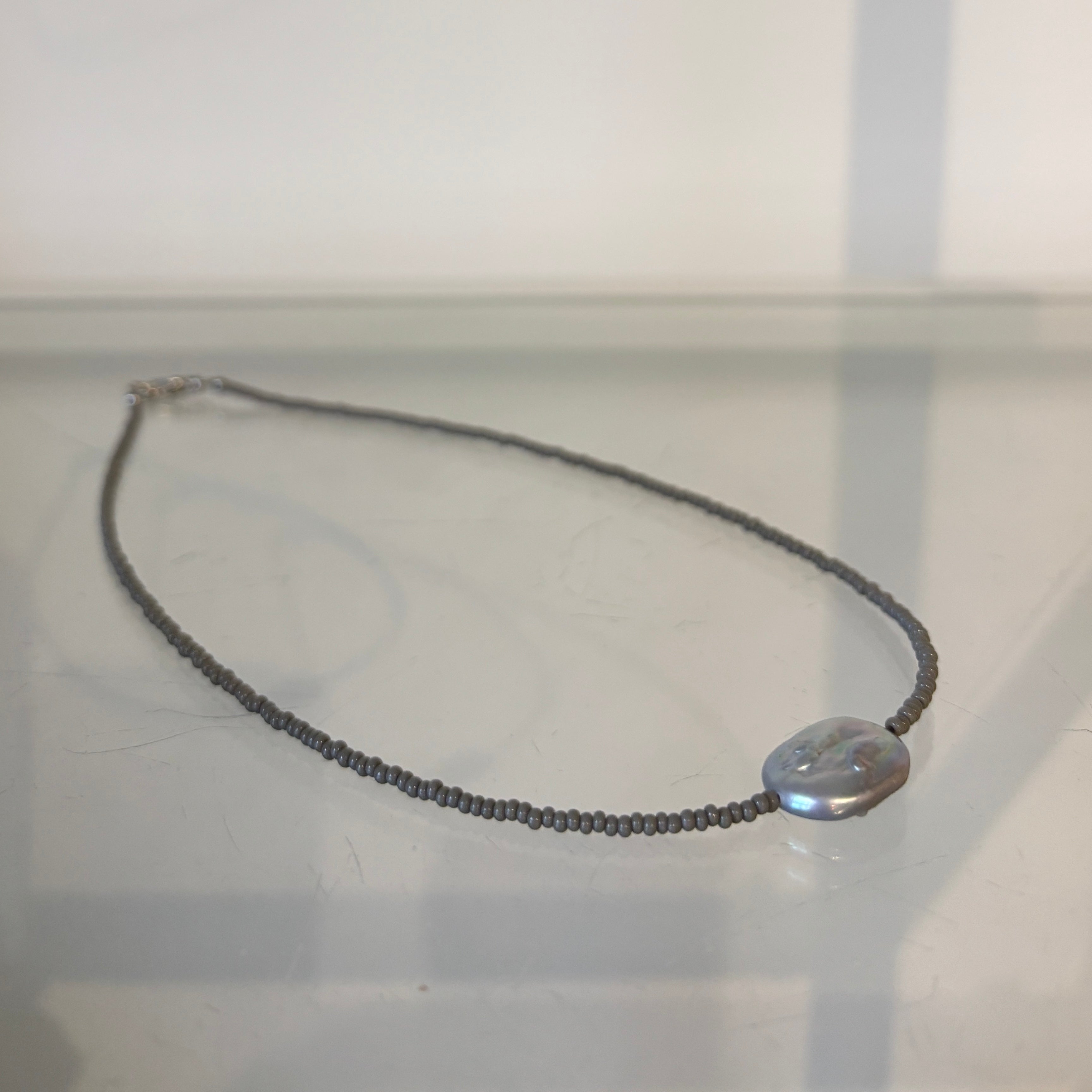 Necklace with a round pendant on a reflective surface