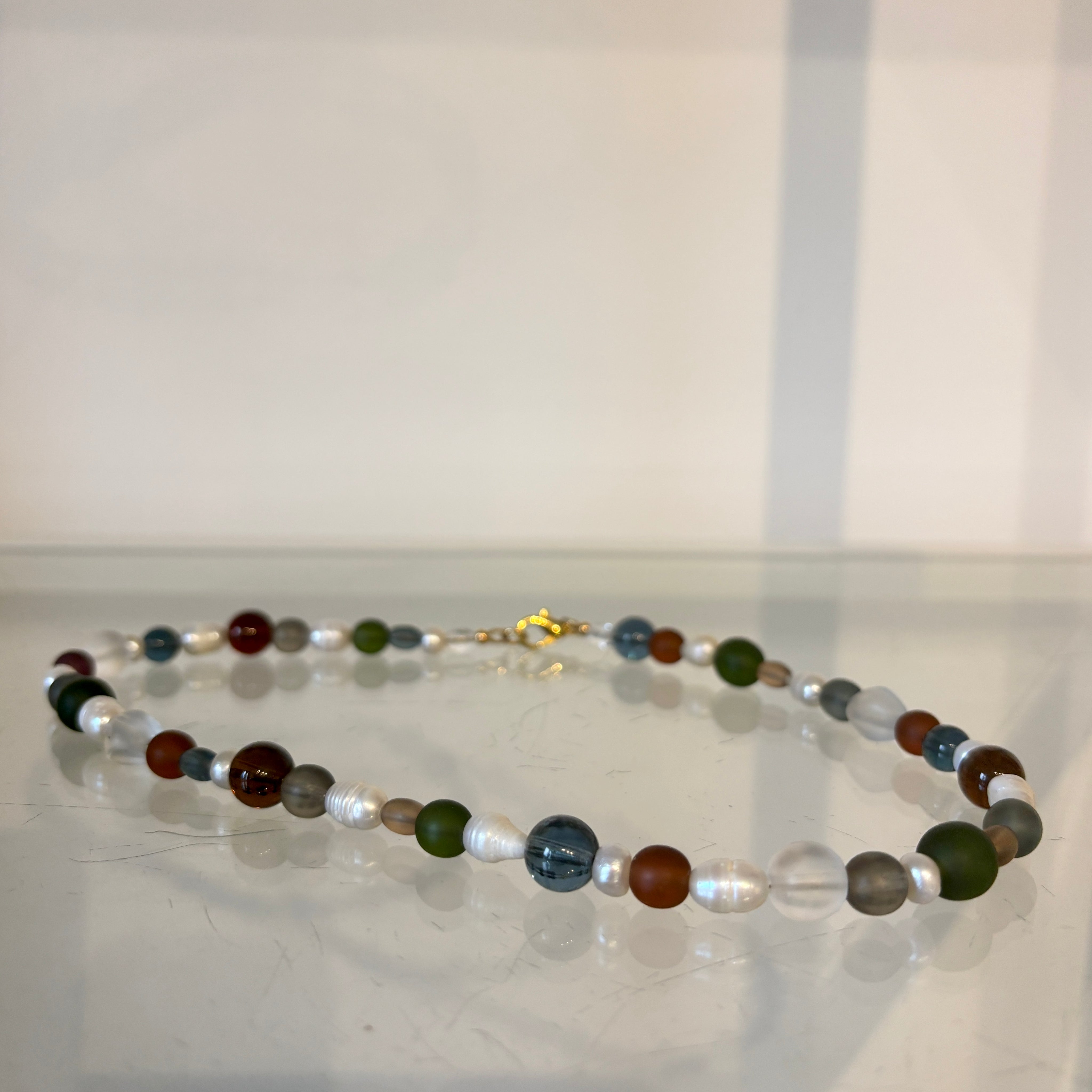 Multicolored beaded necklace on a white surface with a light gray background