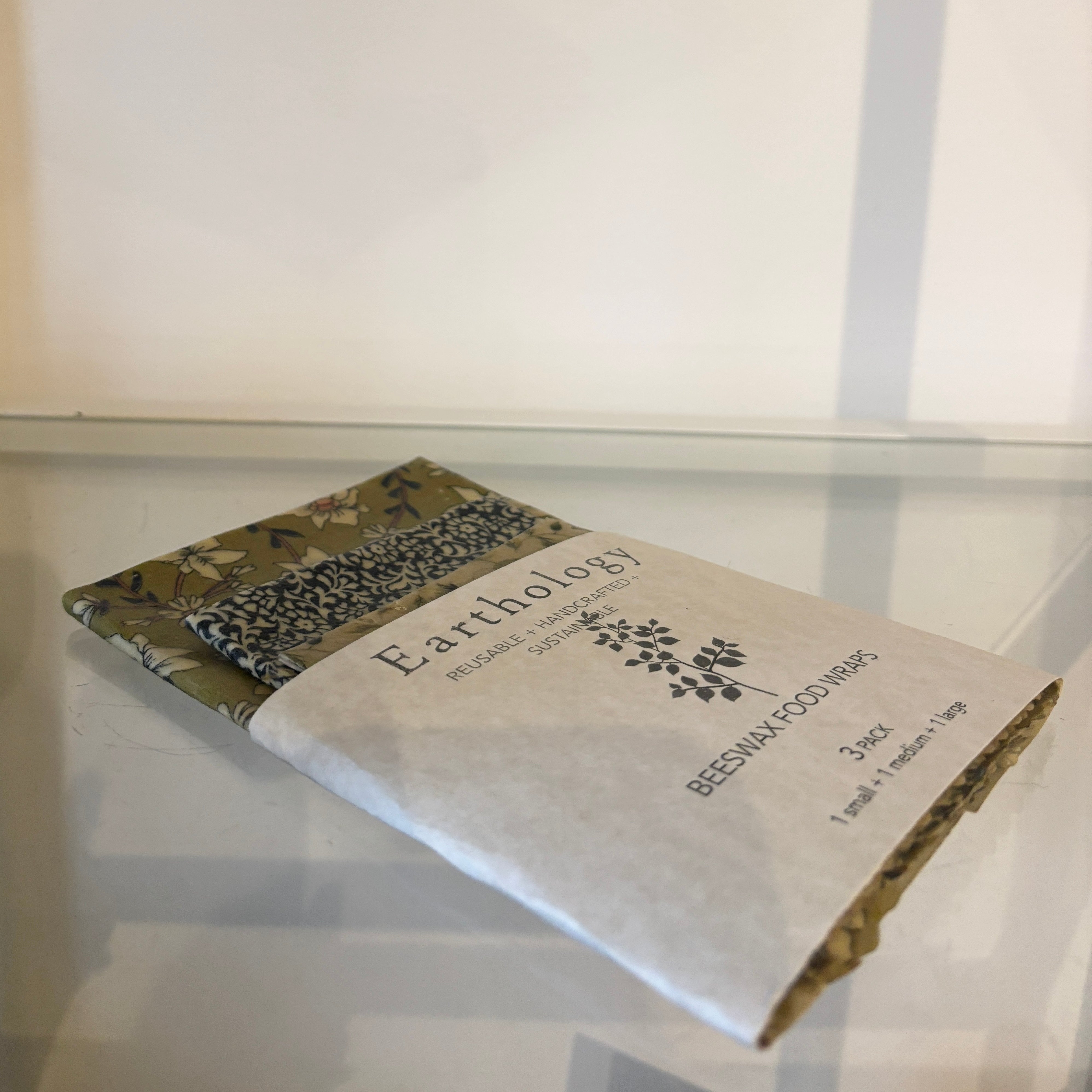 Earthology beeswax food wrap packaging on a reflective surface