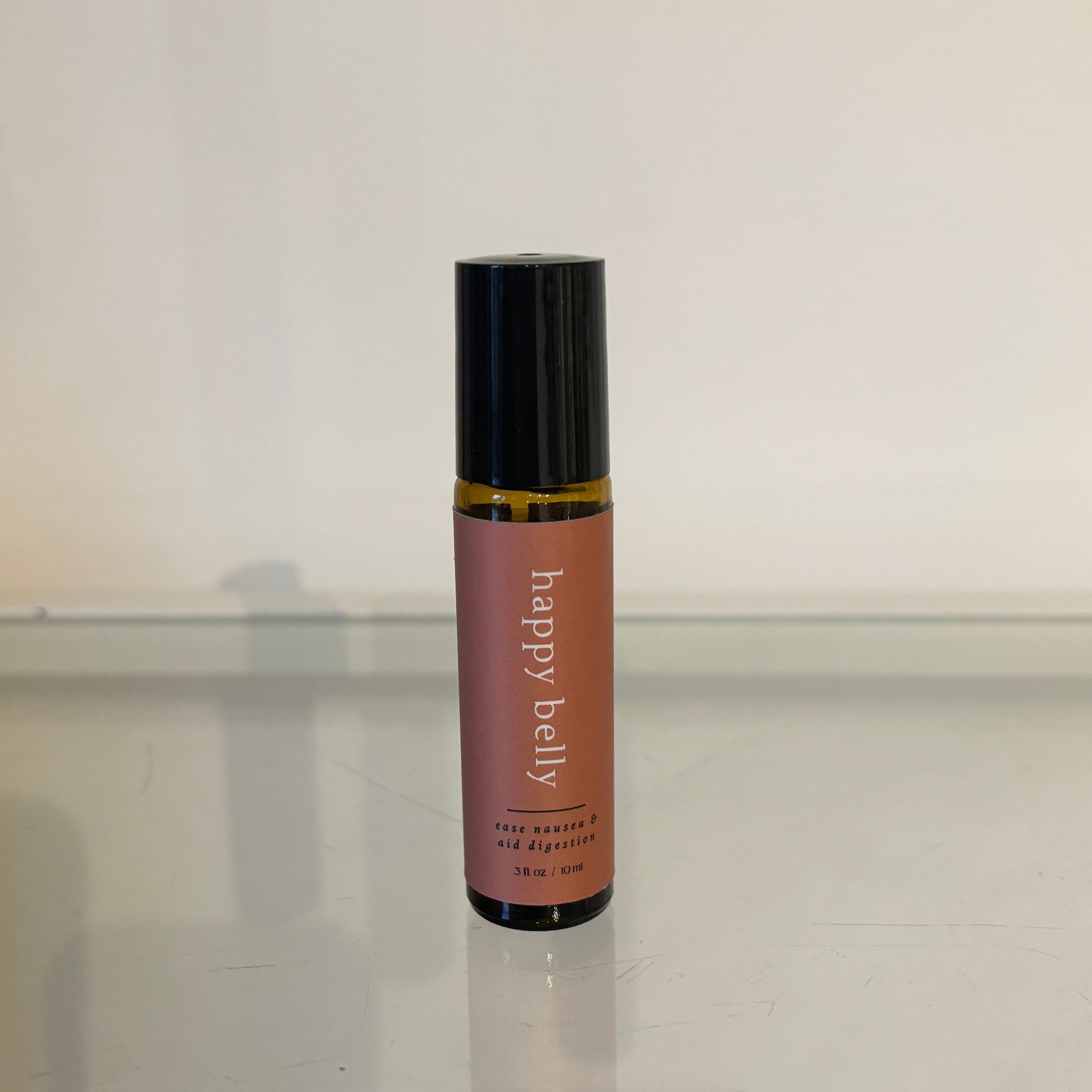 Roll-on bottle with 'happy belly' label on a reflective surface
