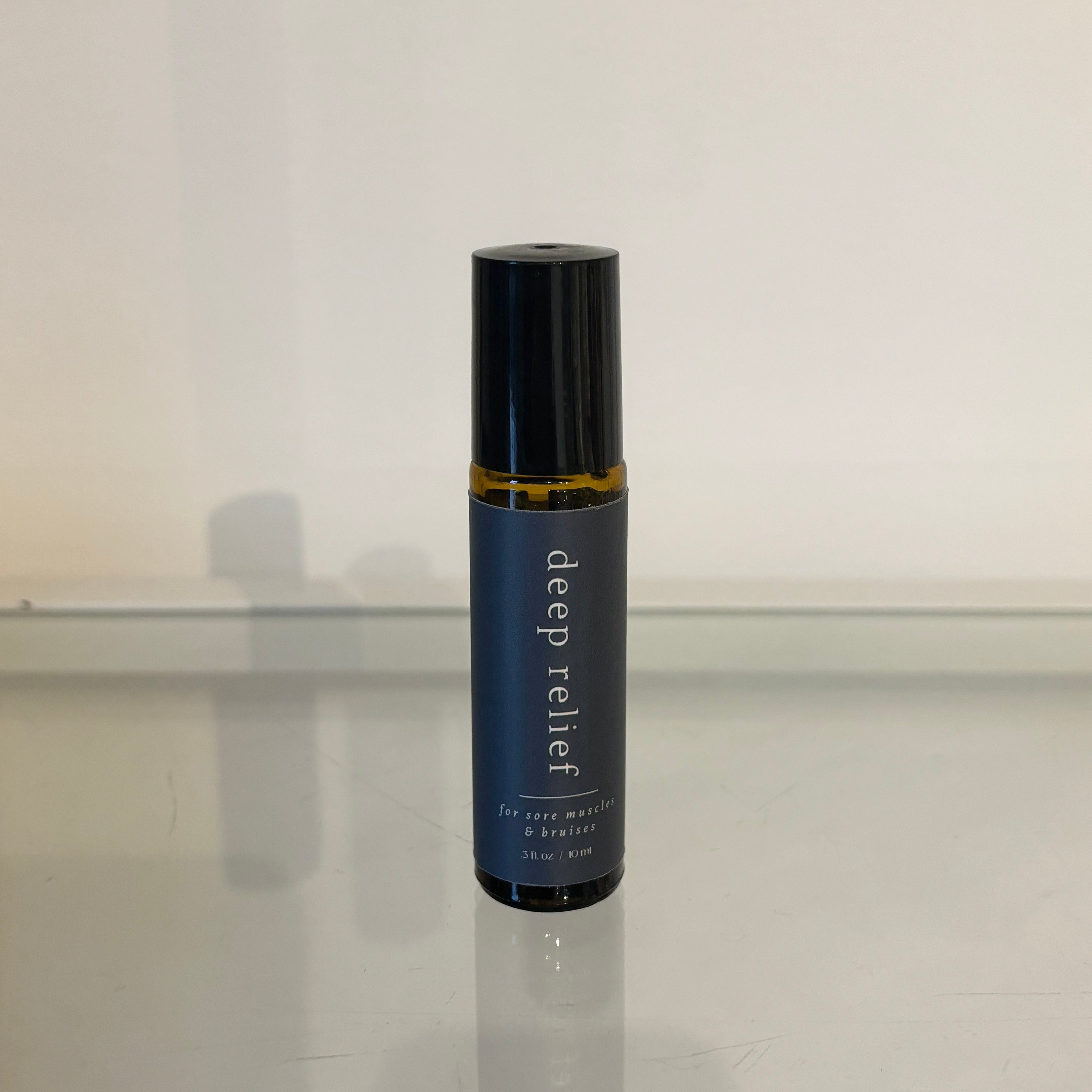 Roll-on bottle labeled 'deep relief' on a reflective surface with a light gray background