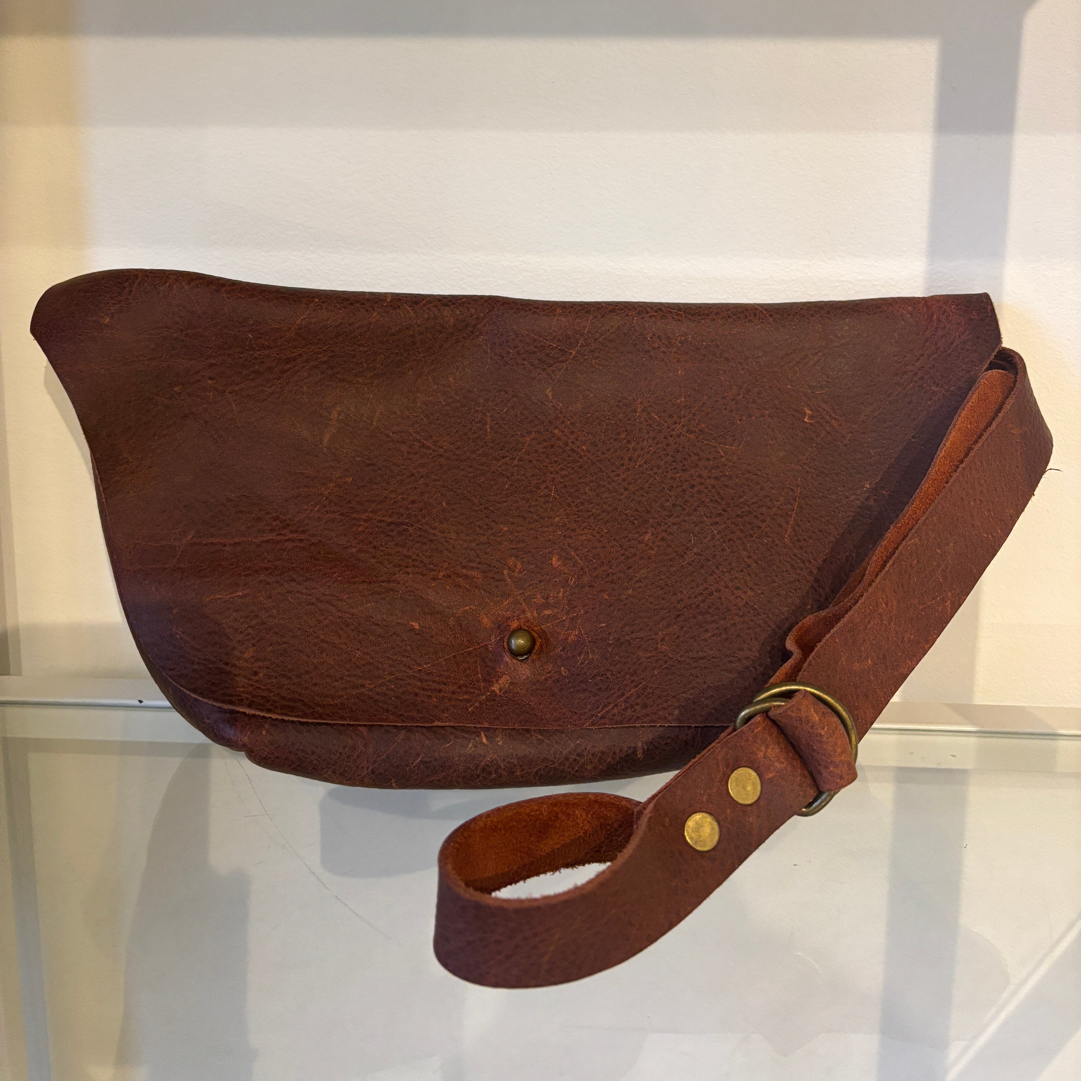 Brown leather bag with strap on a white background