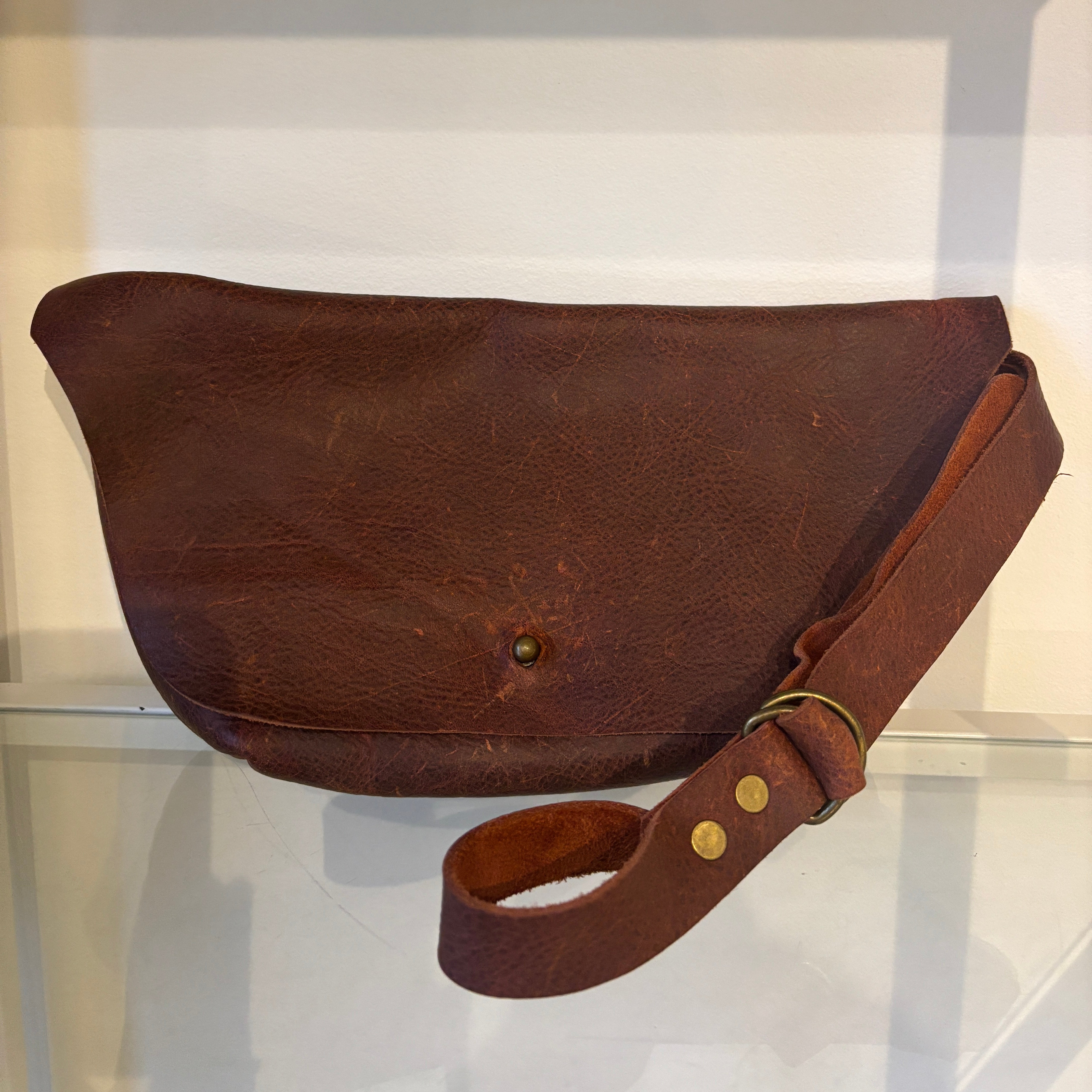 Brown leather bag with strap on a white background
