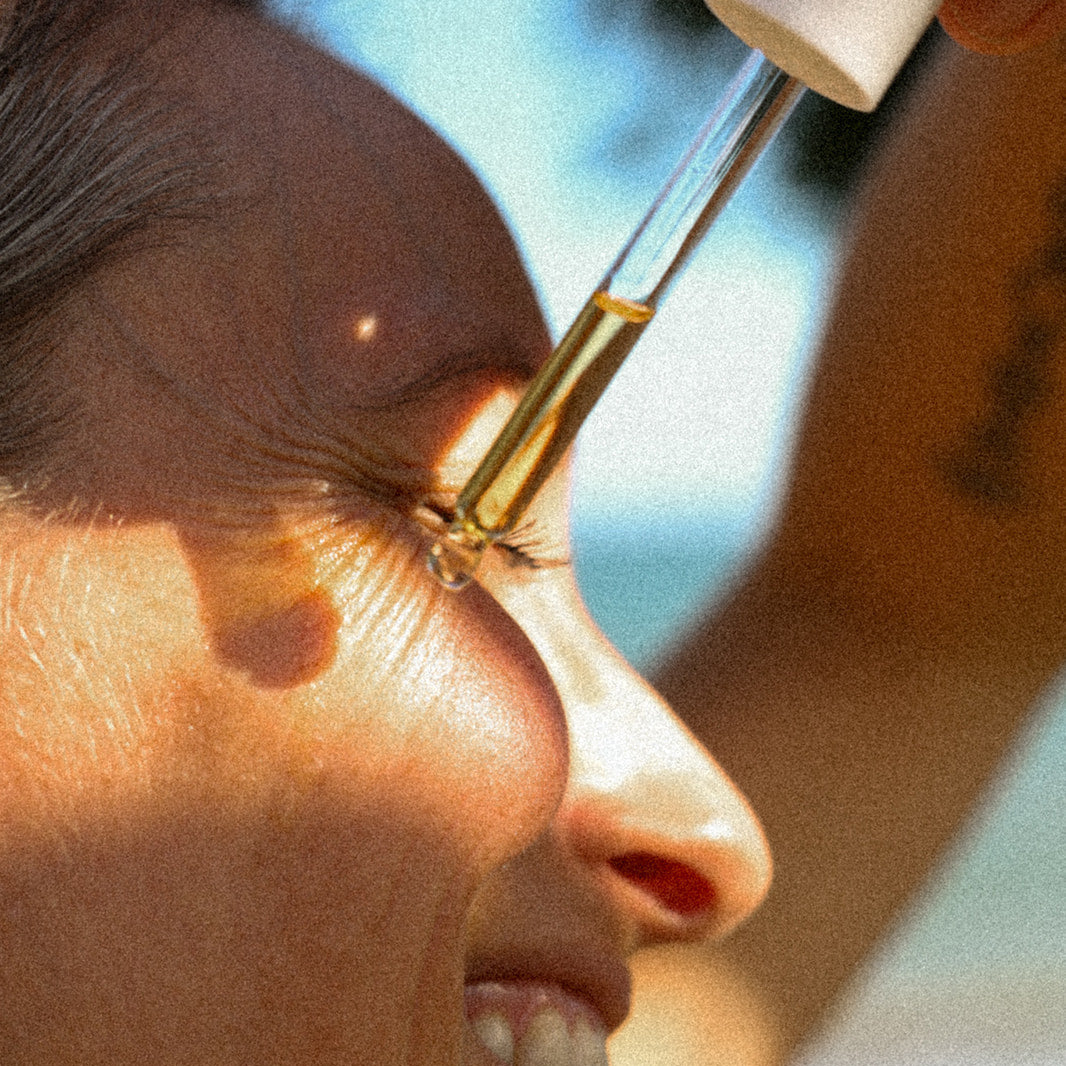 Person applying a dropper of liquid to their eye with a blurred background