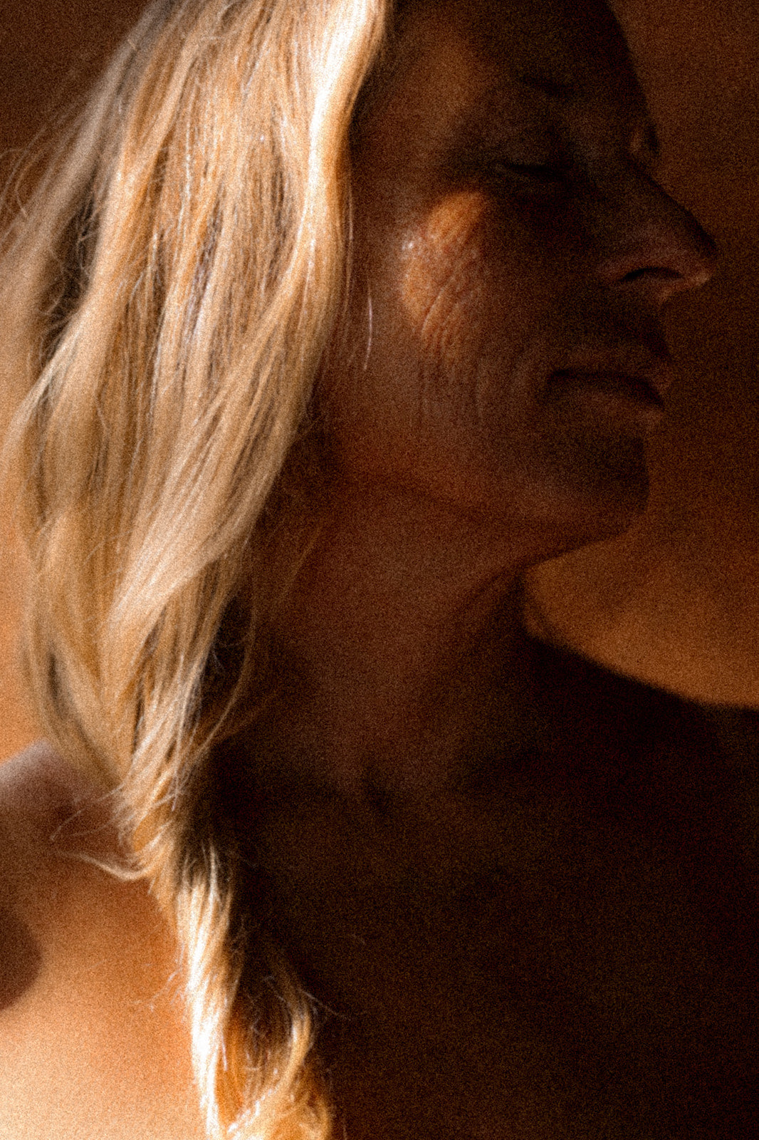 Close-up of a person with blonde hair and a neutral expression, with a warm, soft focus.