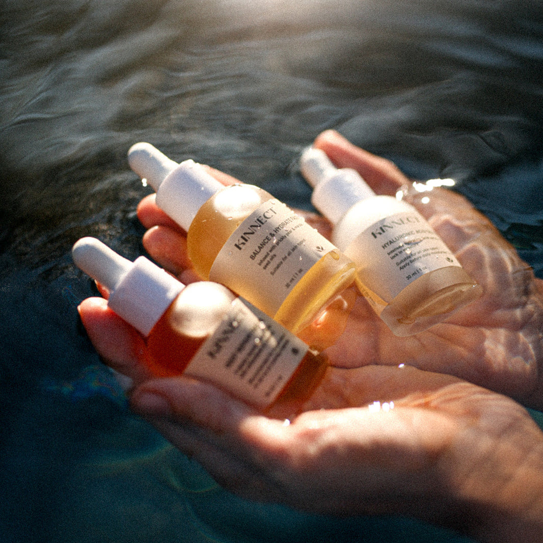 Hand holding three dropper bottles with a blurred natural background