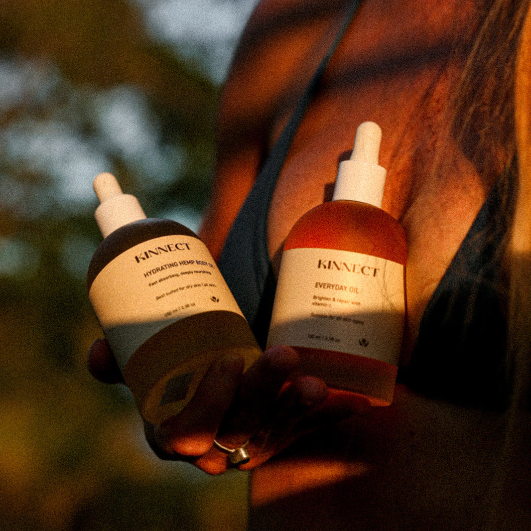 Two skincare bottles held by a person with a blurred natural background