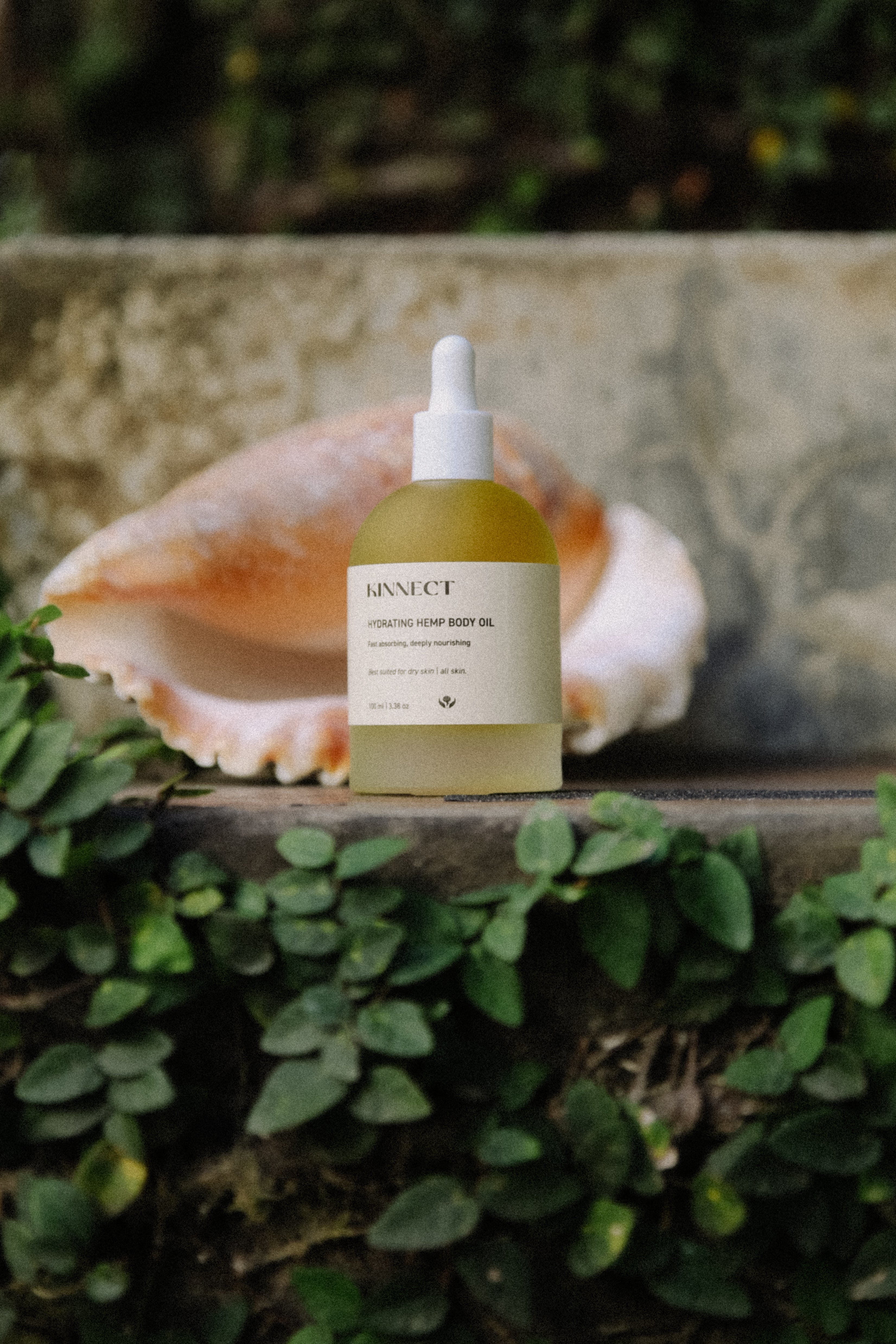 Kinnect Hydrating Hemp Body Oil bottle with dropper on a natural background
