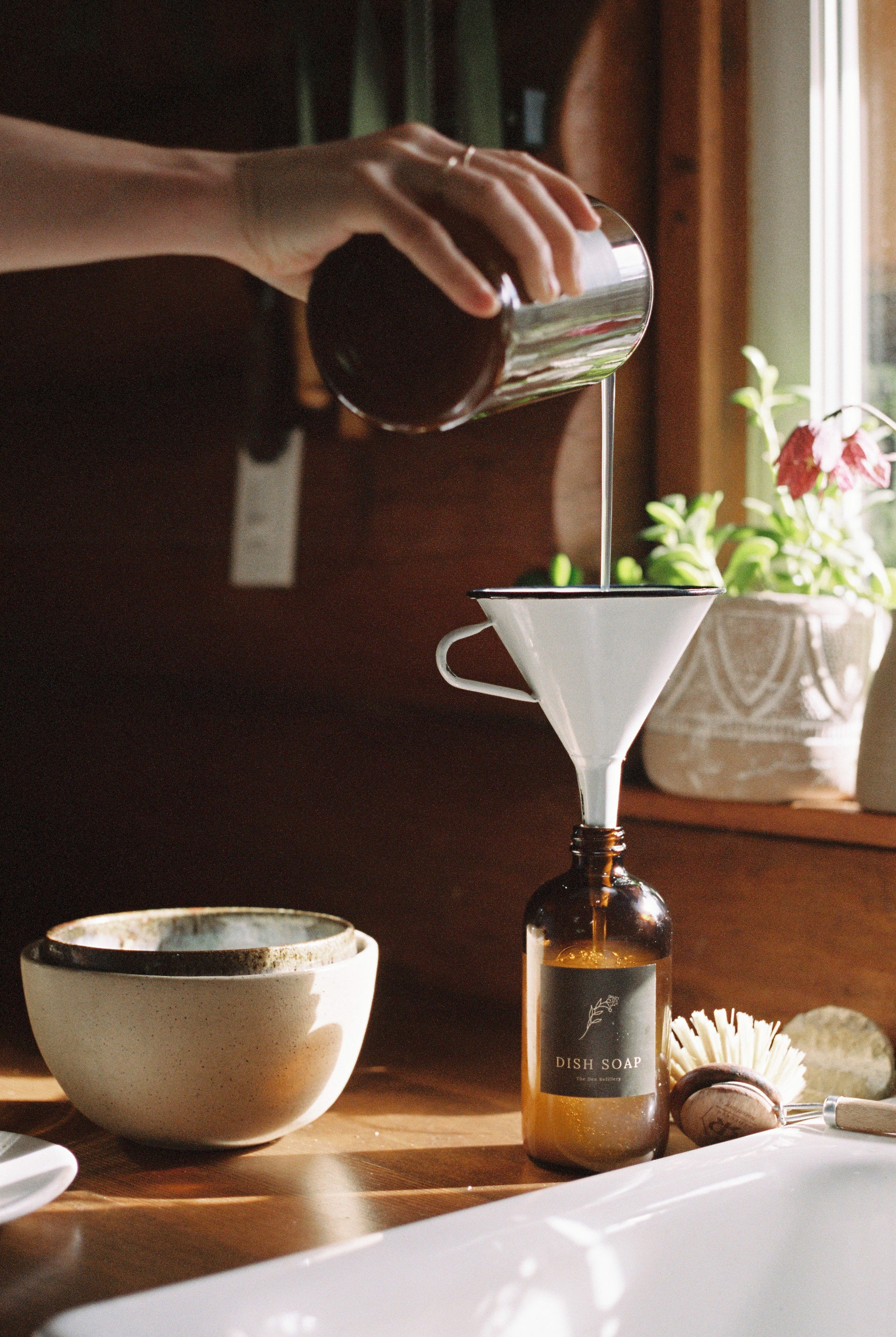Hand pouring soap into funnel