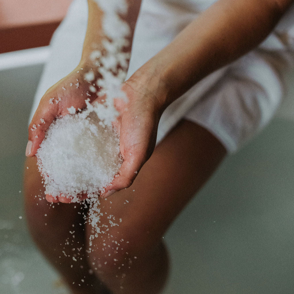 Model holds bath soak as it is poured into her hands and then into the bath