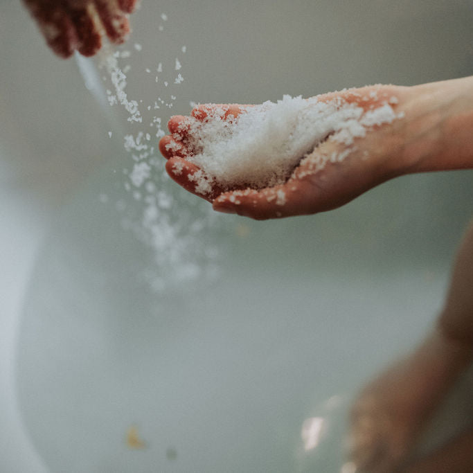 Model holds bath soak as it is poured into her hands and then into the bath