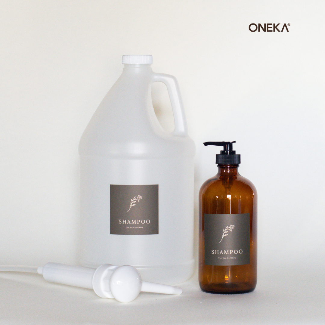 The Den Refillery Shampoo Refill Kit with a 4 Litre jug of Oneka Shampoo and an amber glass bottle.