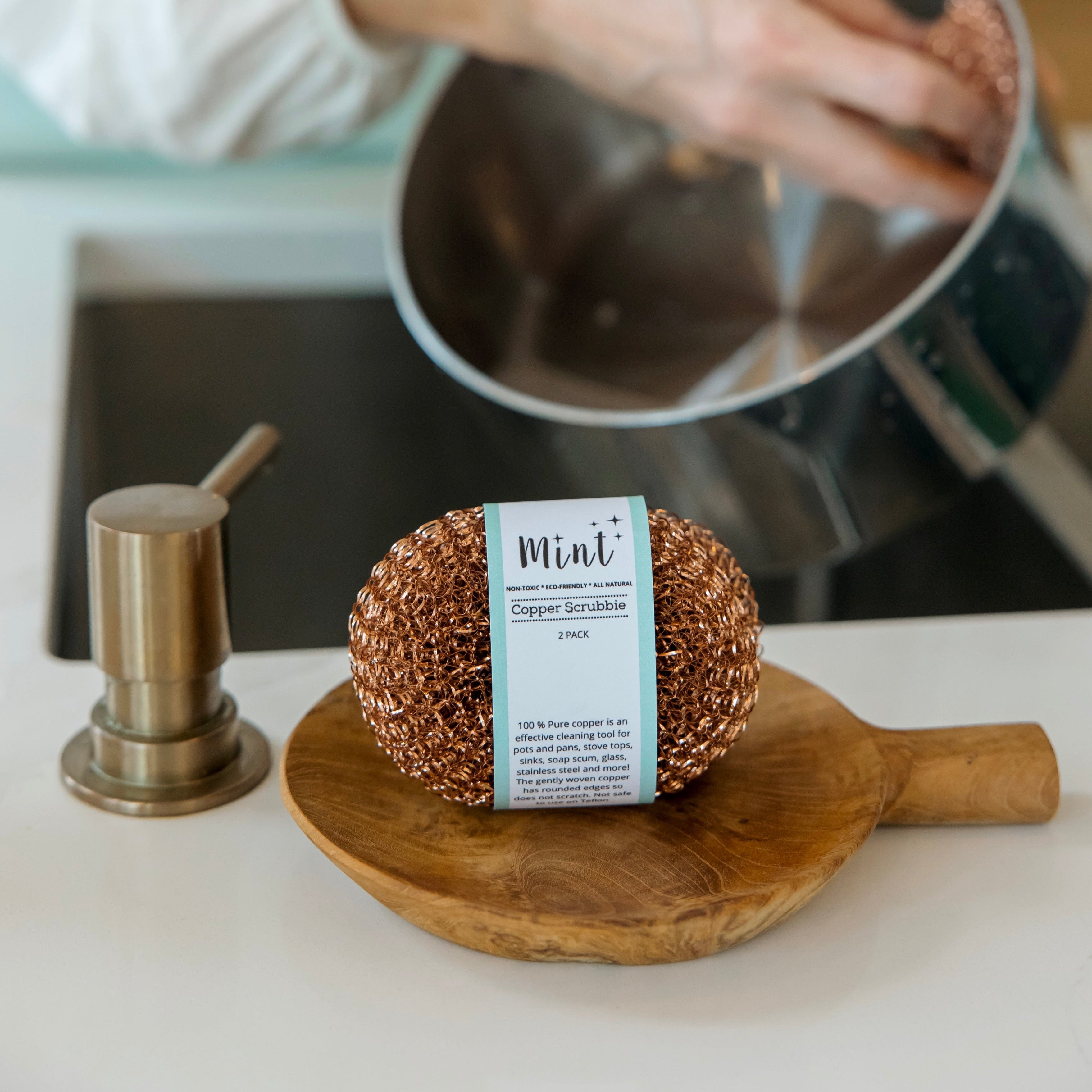 Two copper sponges are used to clean a pot in the background