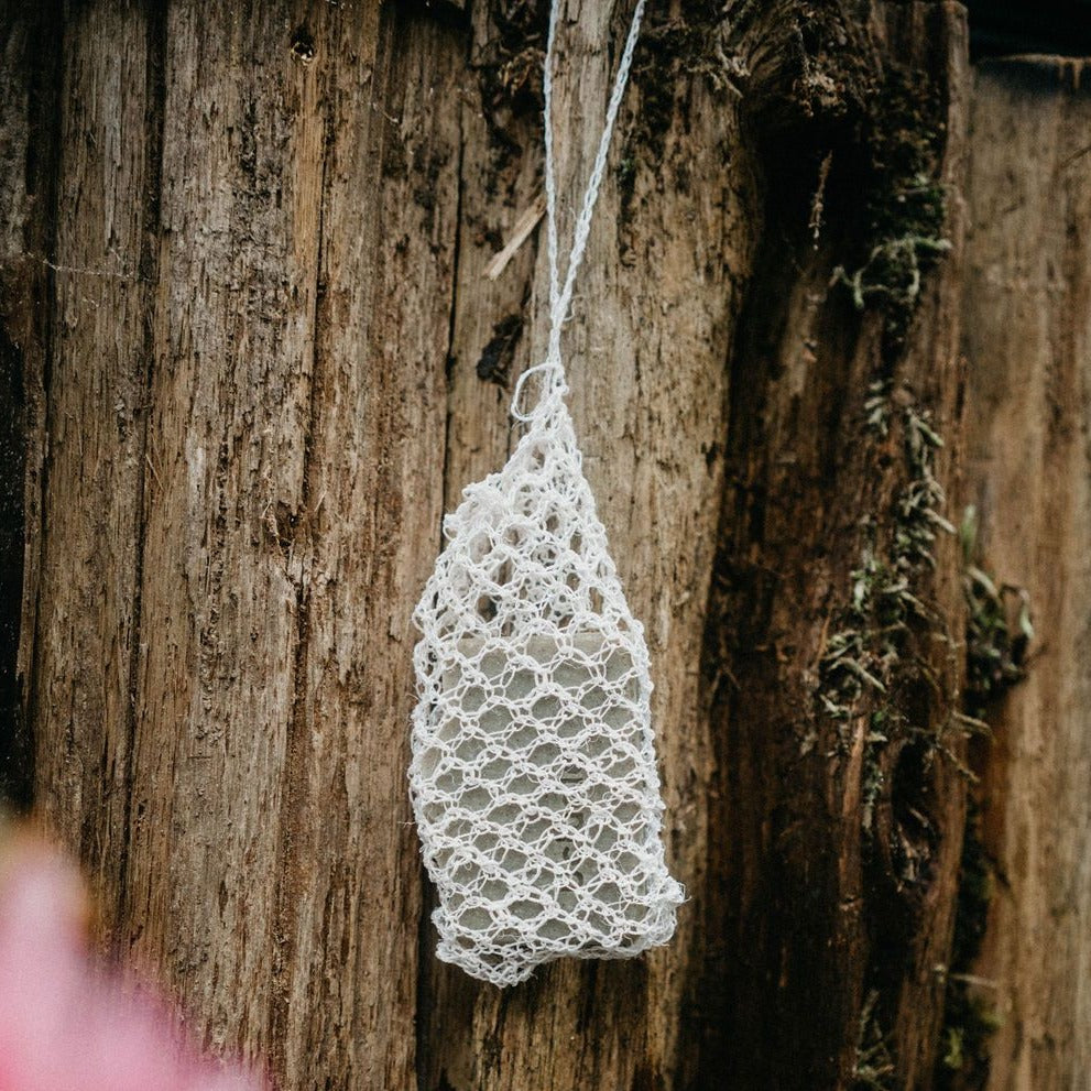 An agave body cloth with a Den Refillery beach soap hanging from a tree with a woodsy theme