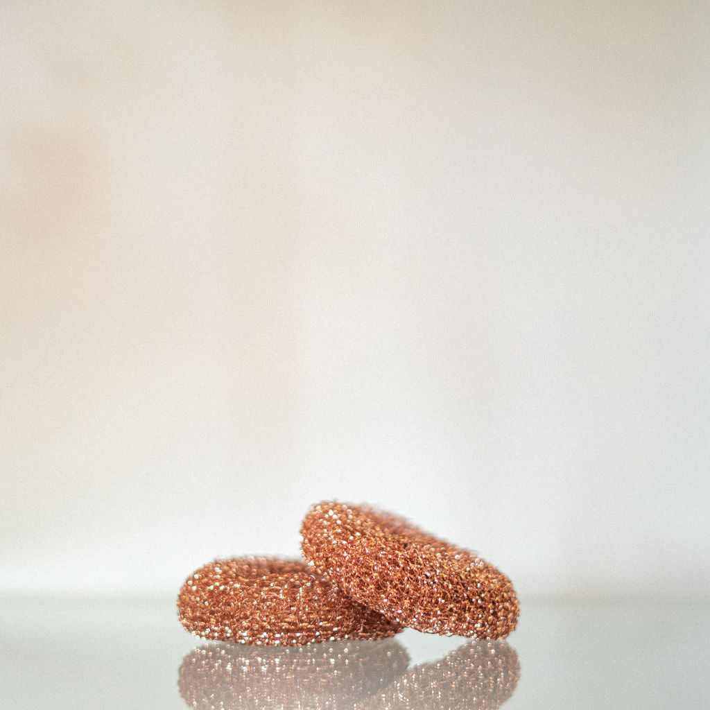 A copper sponge rests on another