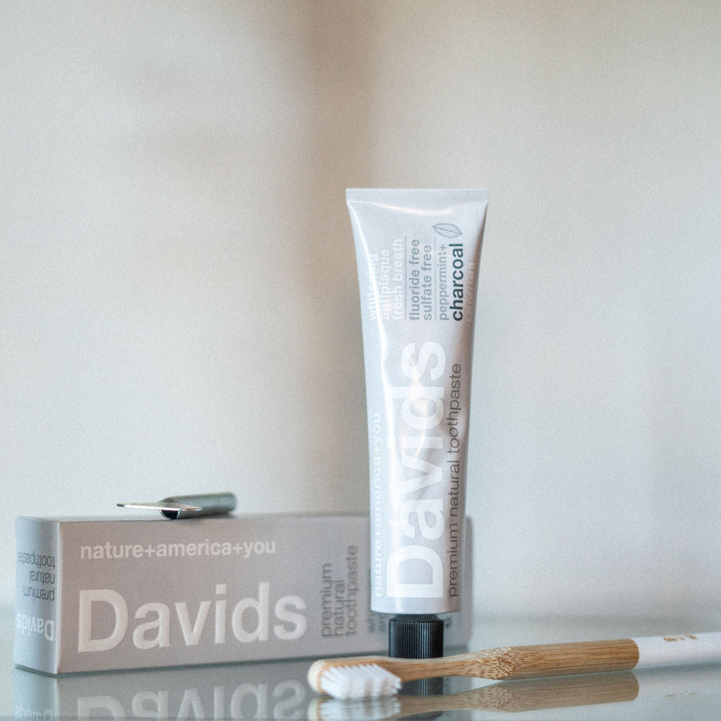 Davids toothpaste in charcoal with a bamboo toothbrush in the foreground