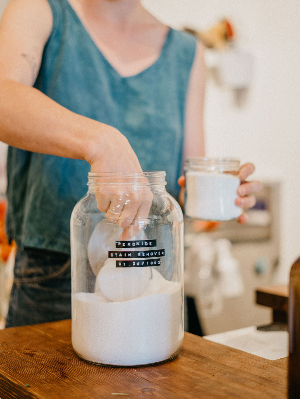 Worker refills their hydrogen peroxide and baking soda into their smaller glass container.