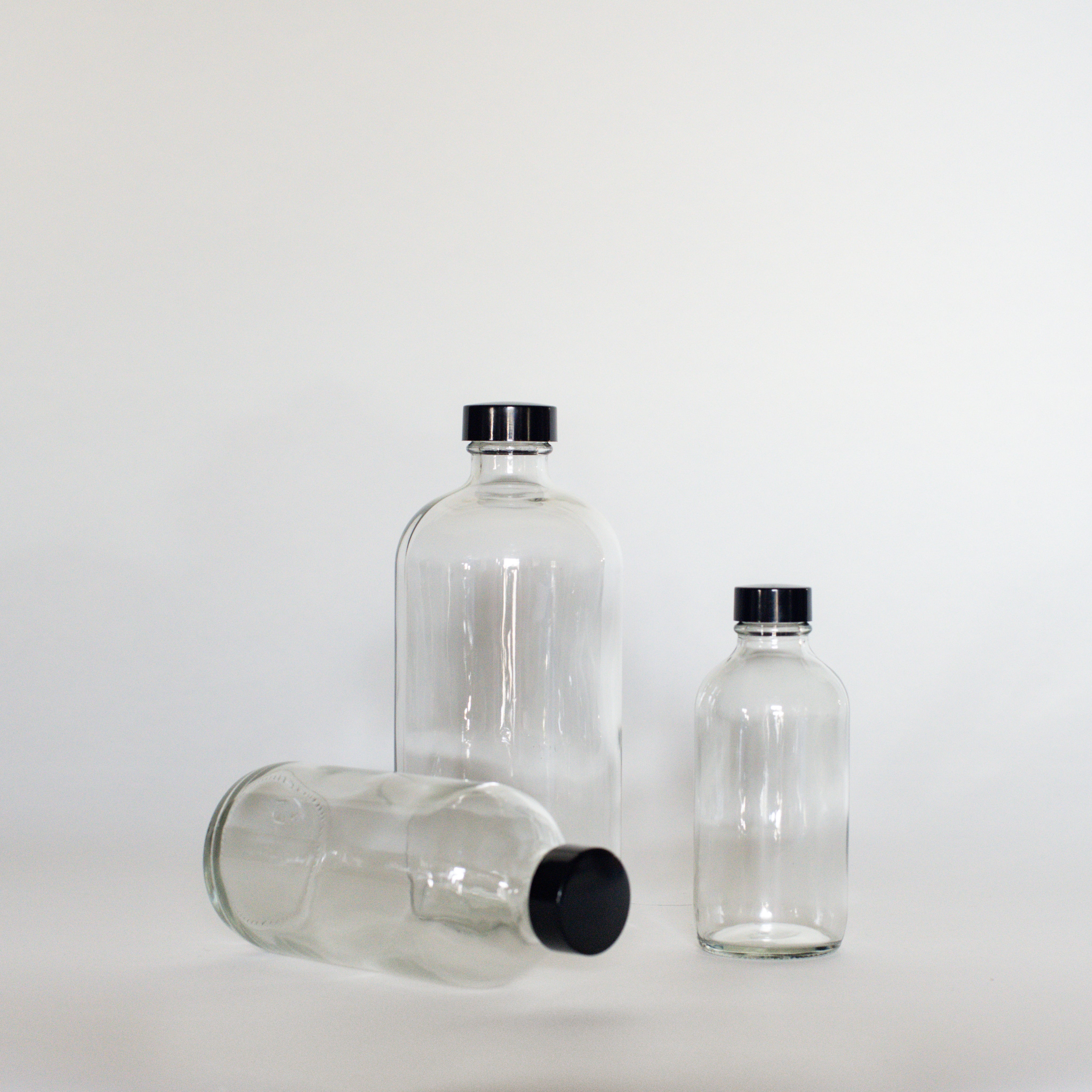 Three clear glass bottles with black twist on caps