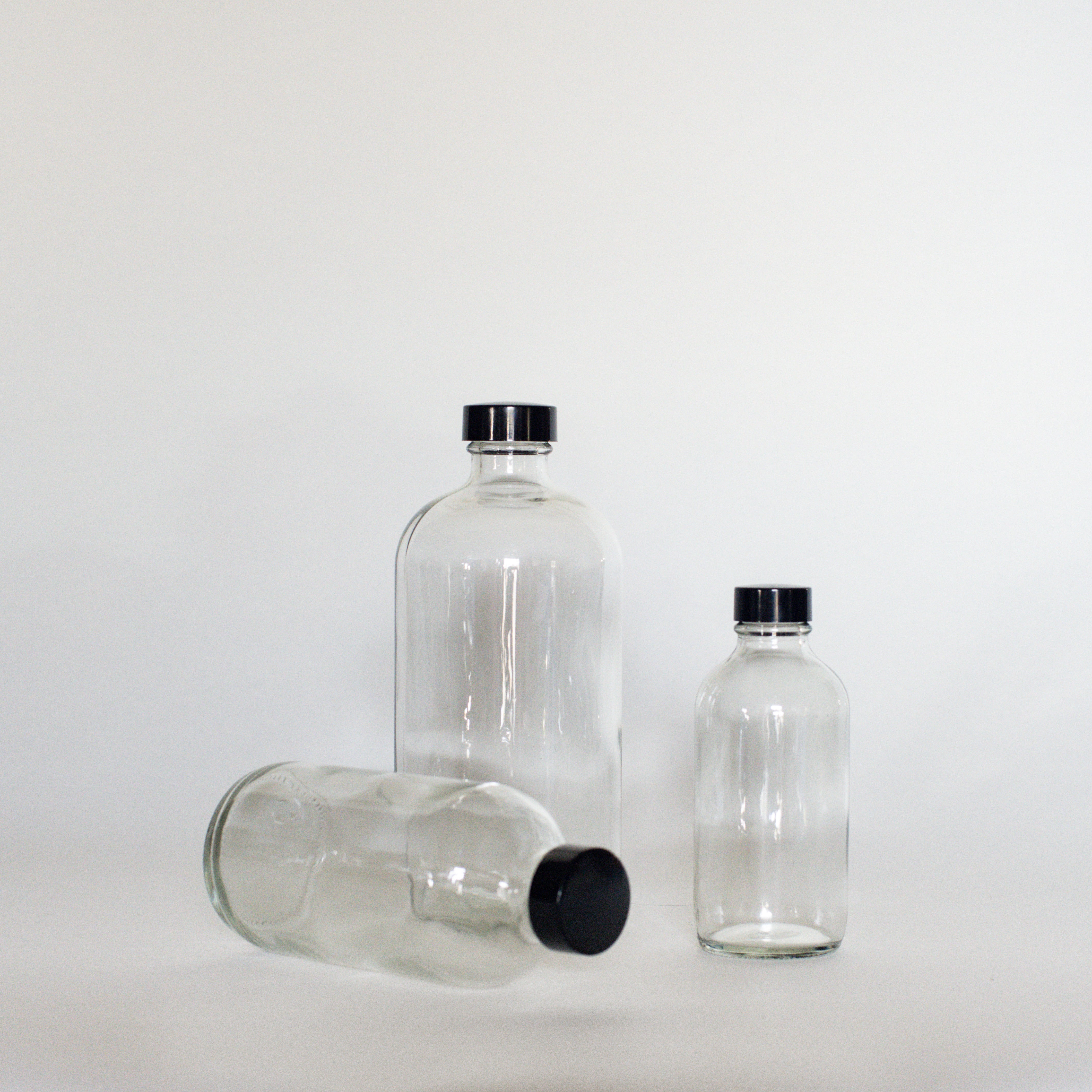 Three clear glass bottles with black twist on caps