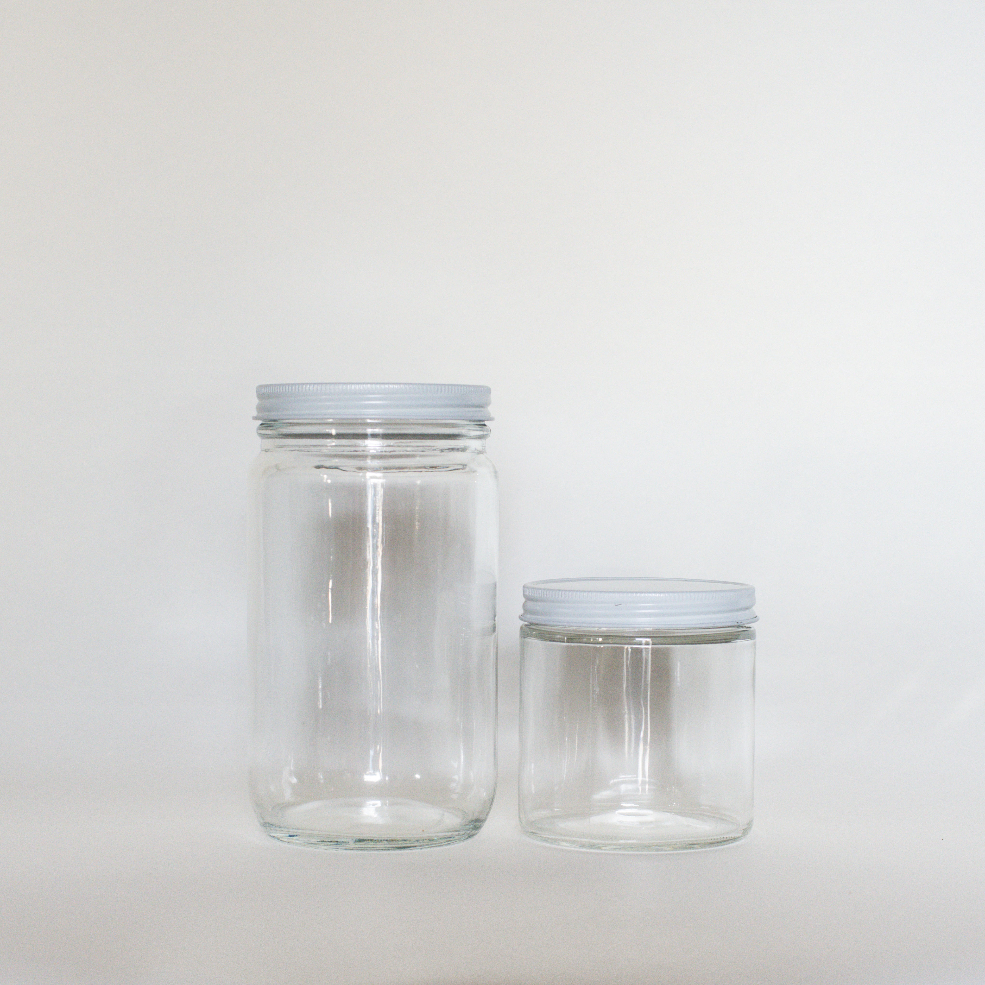 Two of our clear glass jars with white screw on lids. The left is 950ml and the right is 500ml